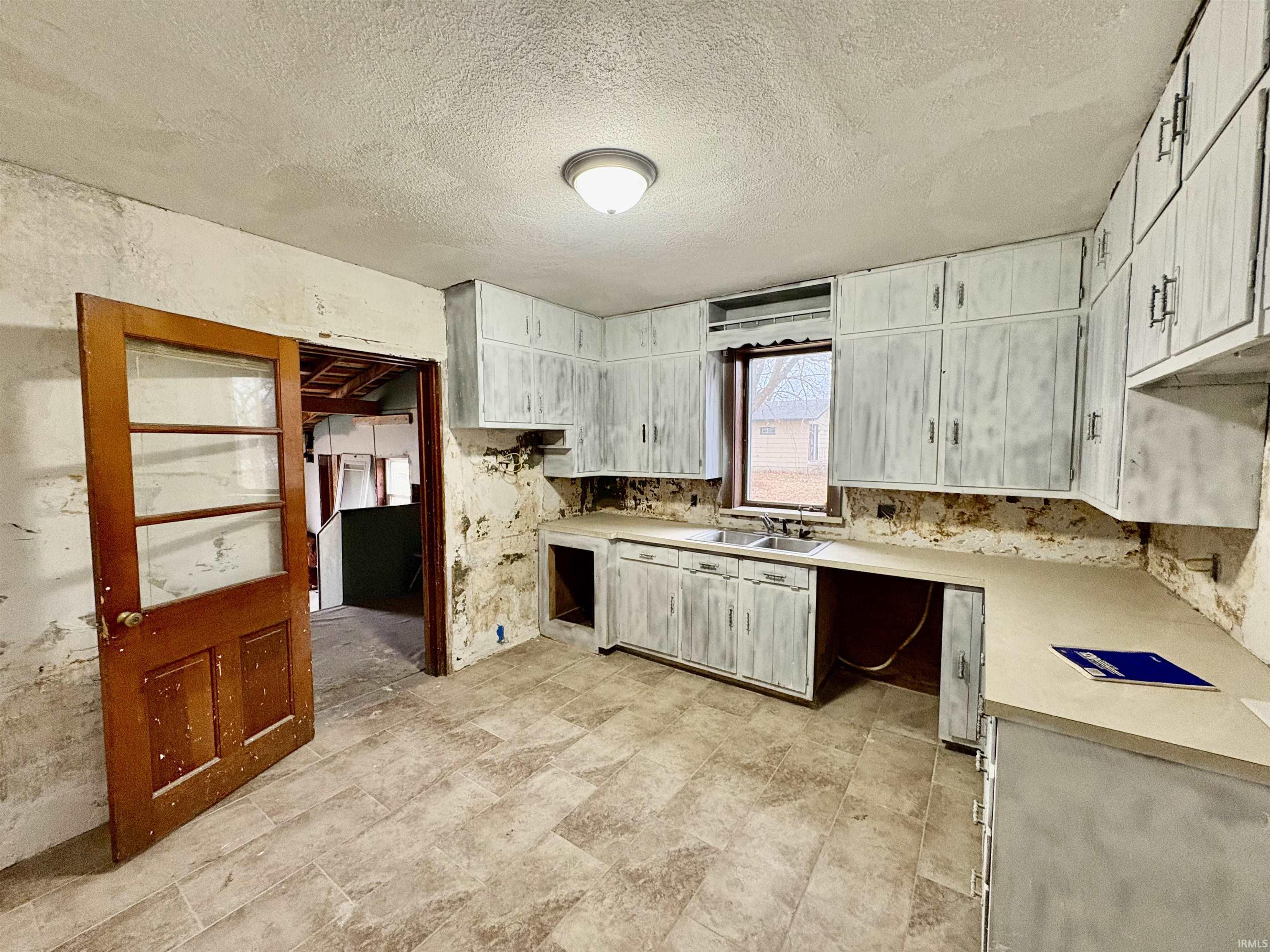 Kitchen featuring a textured ceiling, light countertops, and white cabinetry