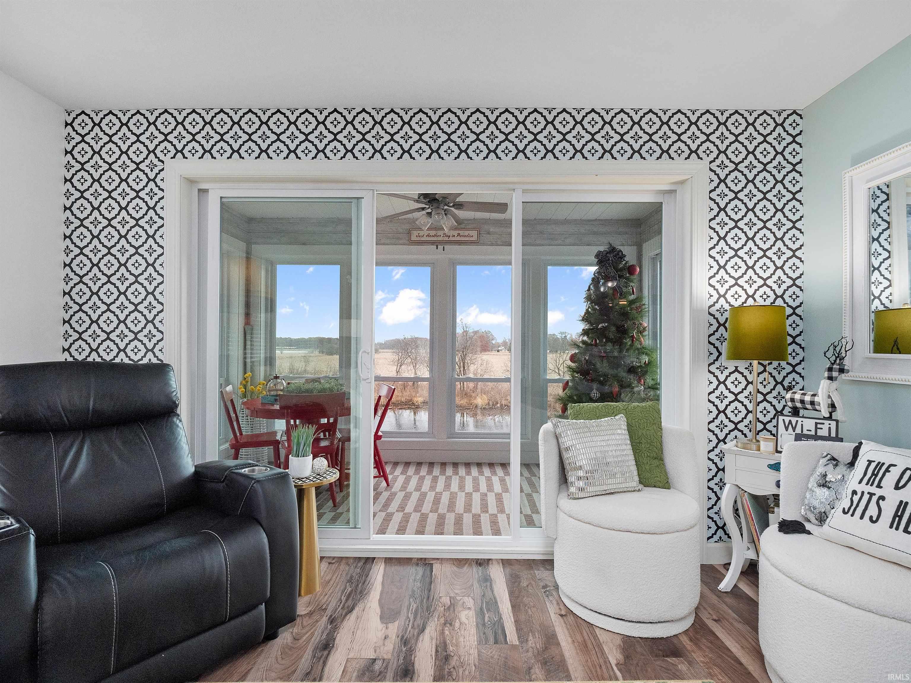 Sitting room with wallpapered walls, wood finished floors, an accent wall, and ceiling fan