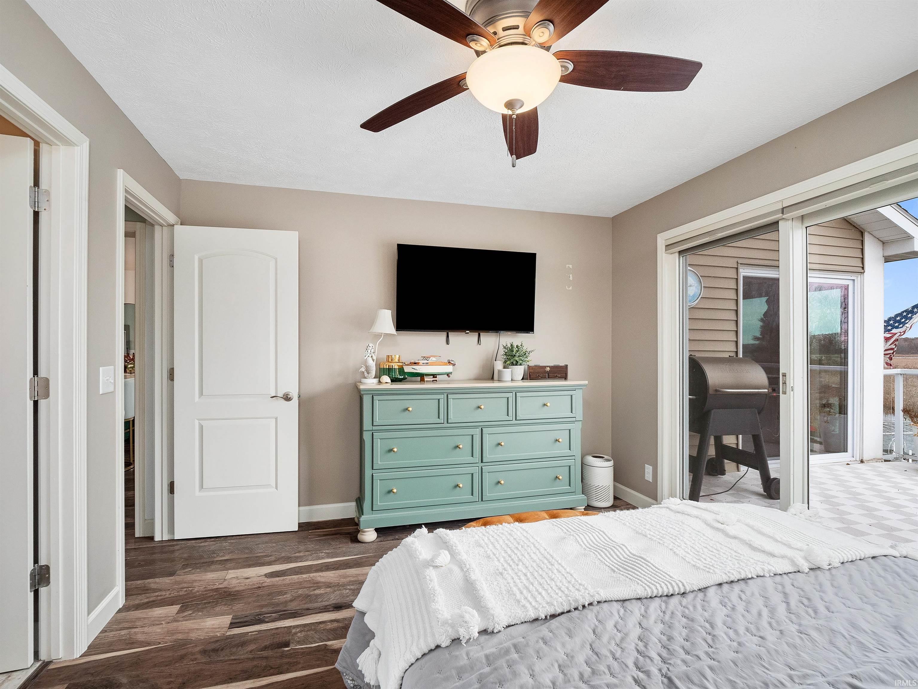 Bedroom with access to outside, dark wood-style flooring, and a ceiling fan