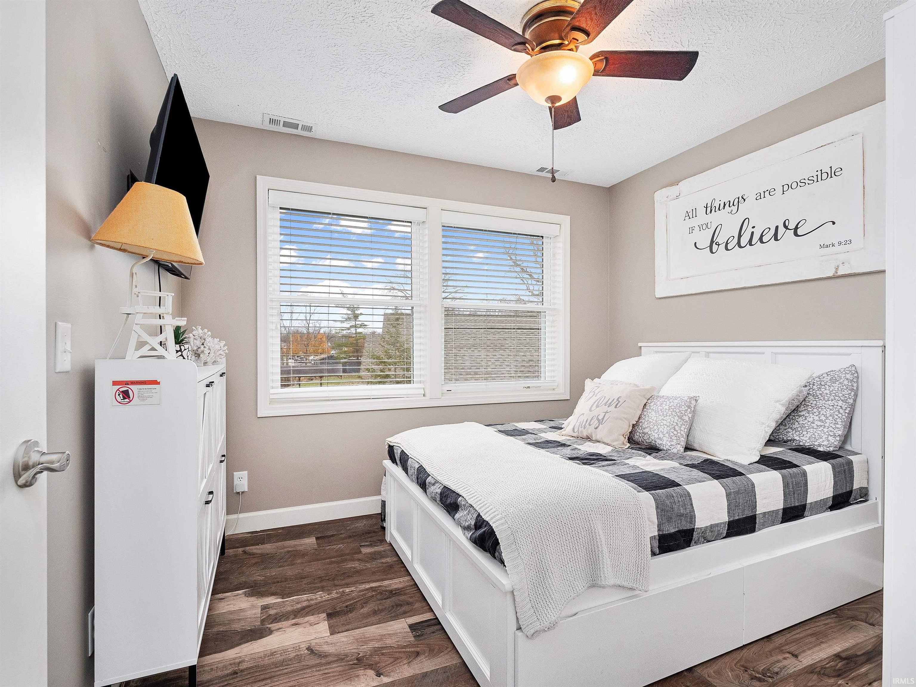 Bedroom with a ceiling fan, dark wood-style floors, and a textured ceiling