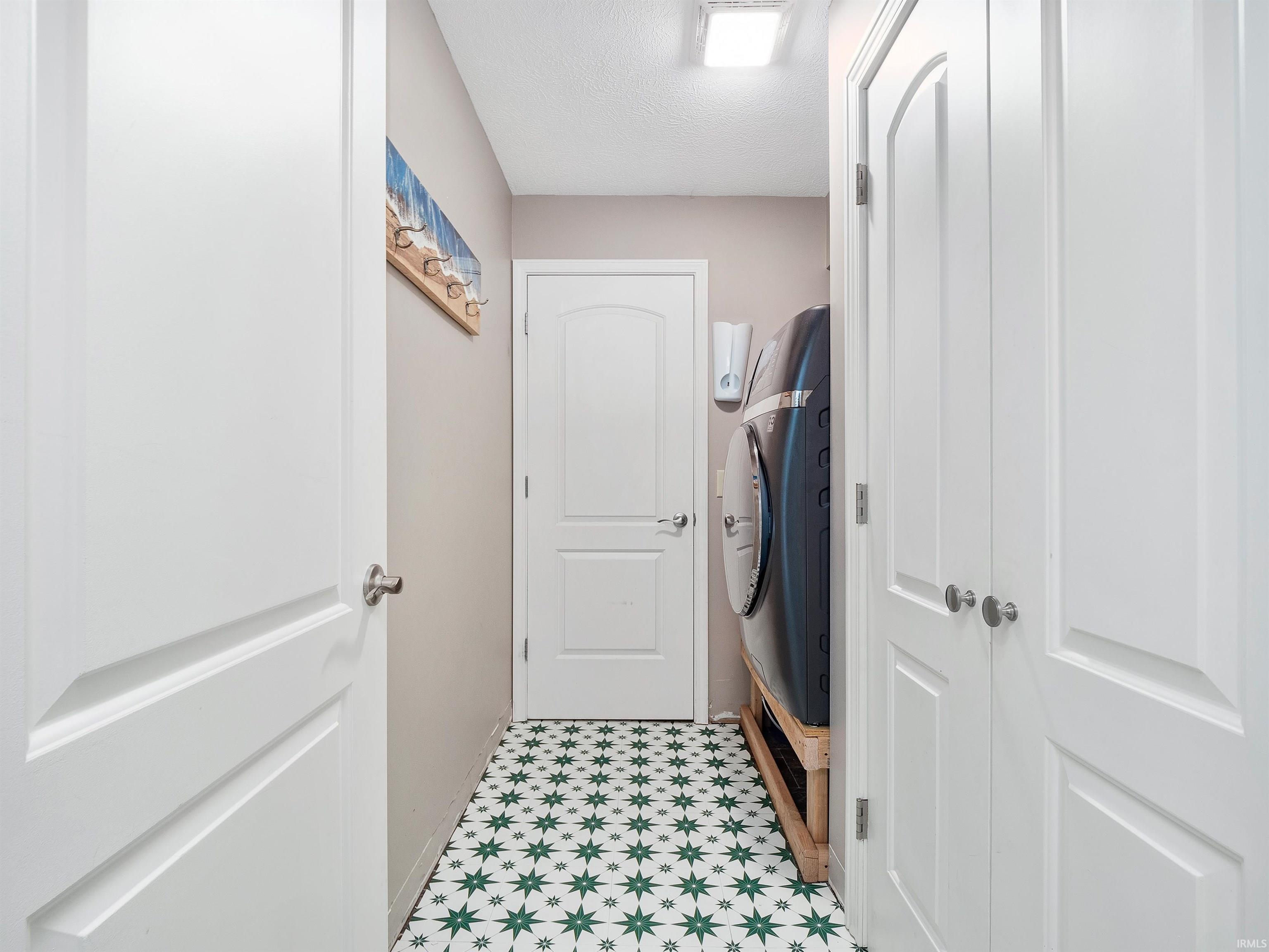 Mudroom featuring light floors and a textured ceiling