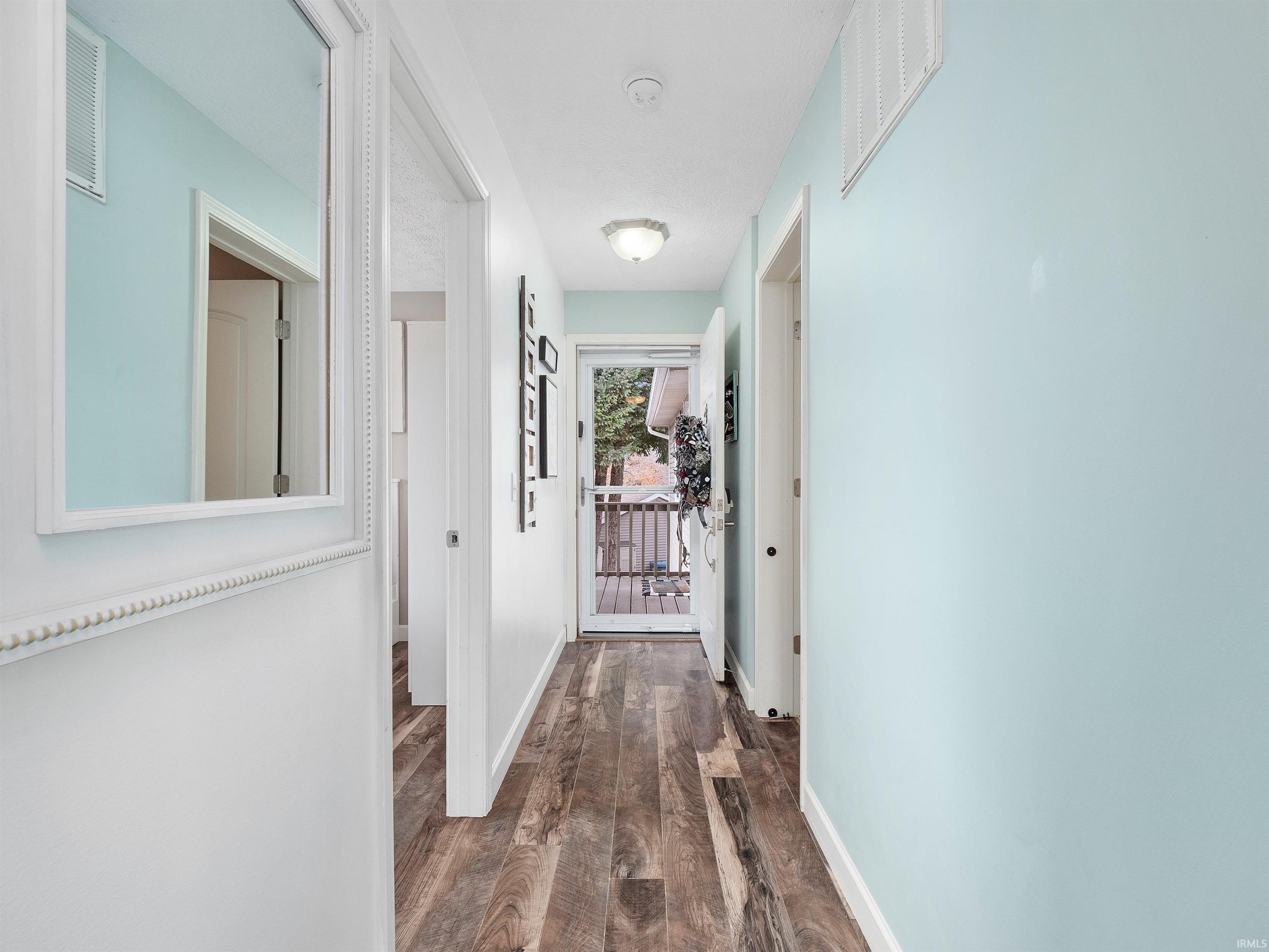 Corridor featuring dark wood-style flooring and baseboards