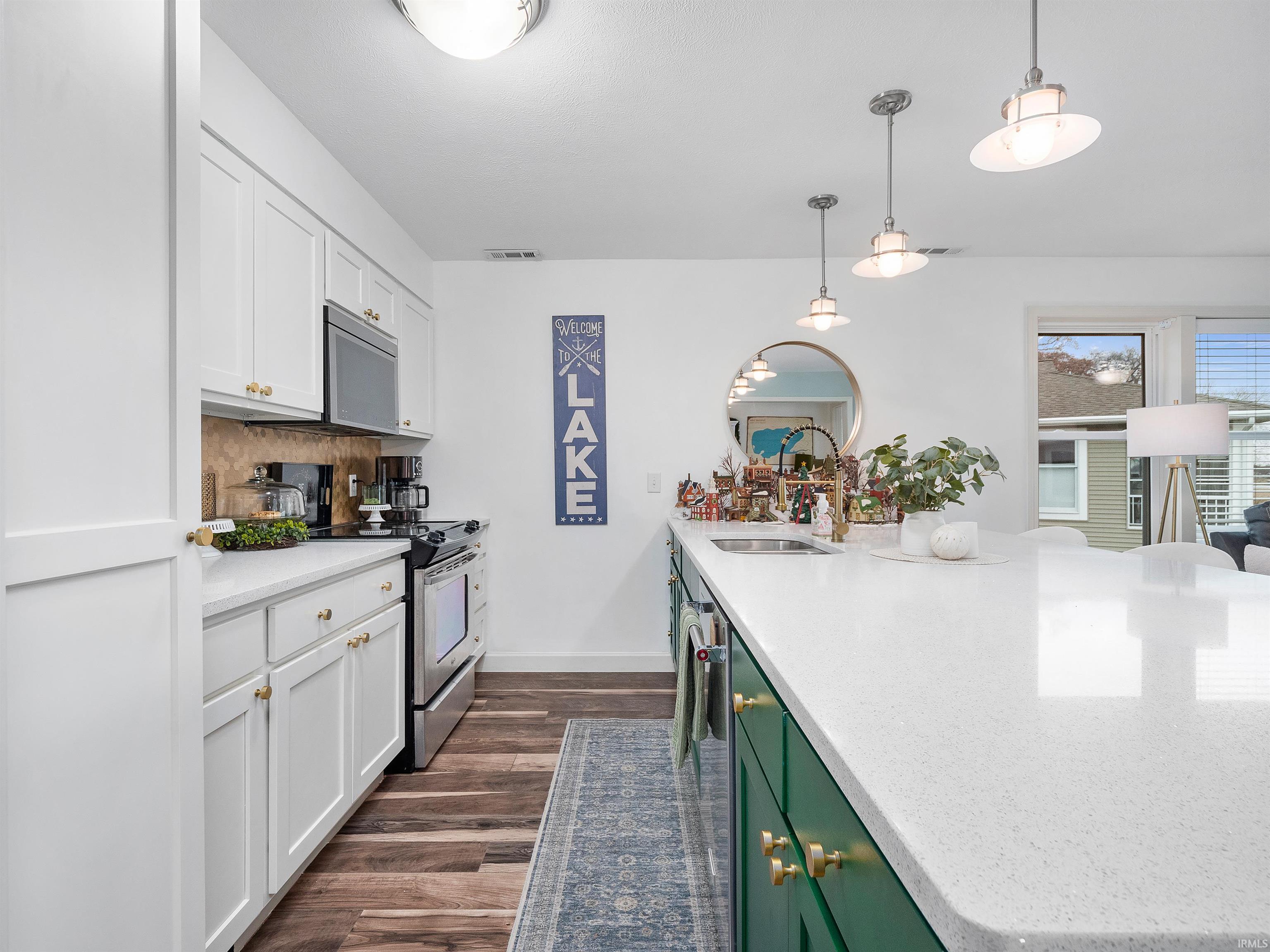 Kitchen featuring white cabinets, pendant lighting, light stone counters, and stainless steel appliances