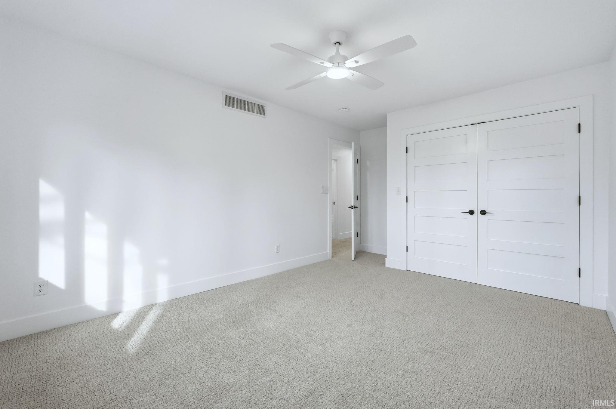 Unfurnished bedroom featuring carpet floors, a closet, and a ceiling fan