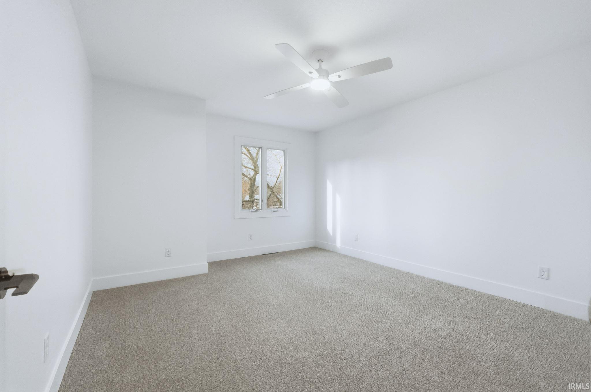 Empty room featuring light carpet and a ceiling fan