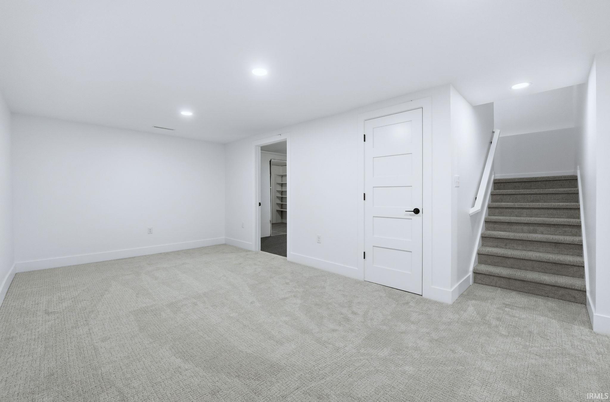 Finished below grade area with light colored carpet, recessed lighting, and stairs