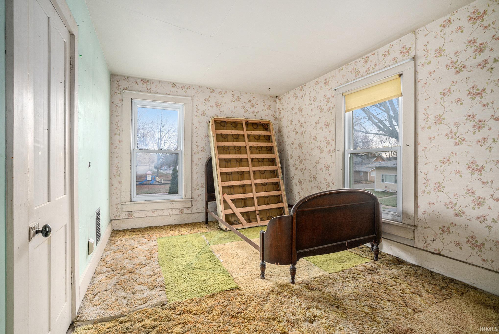 Carpeted bedroom featuring multiple windows and wallpapered walls