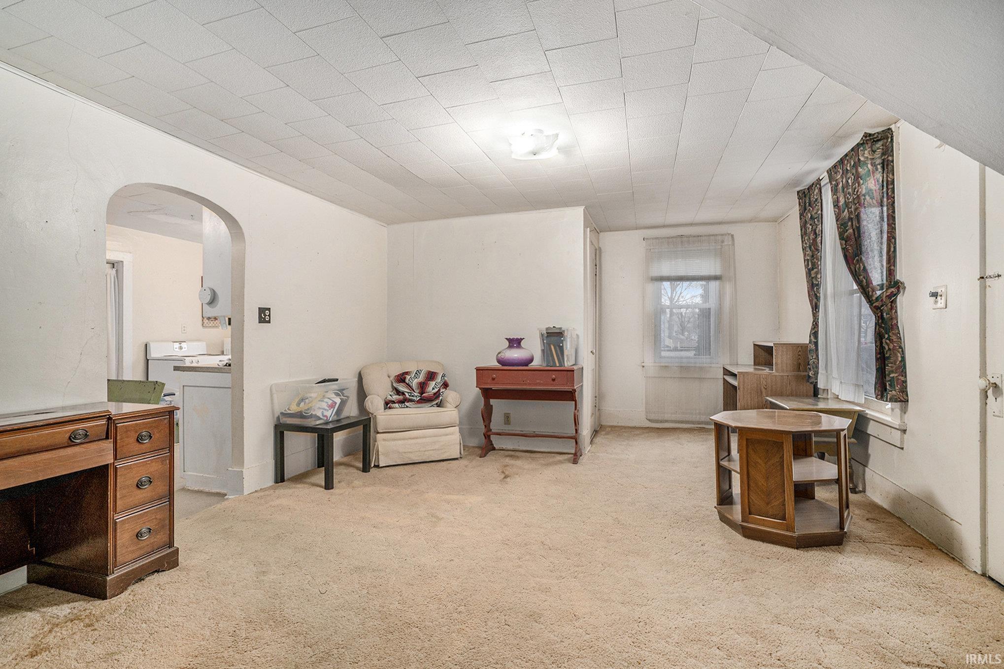 Sitting room featuring arched walkways and light colored carpet
