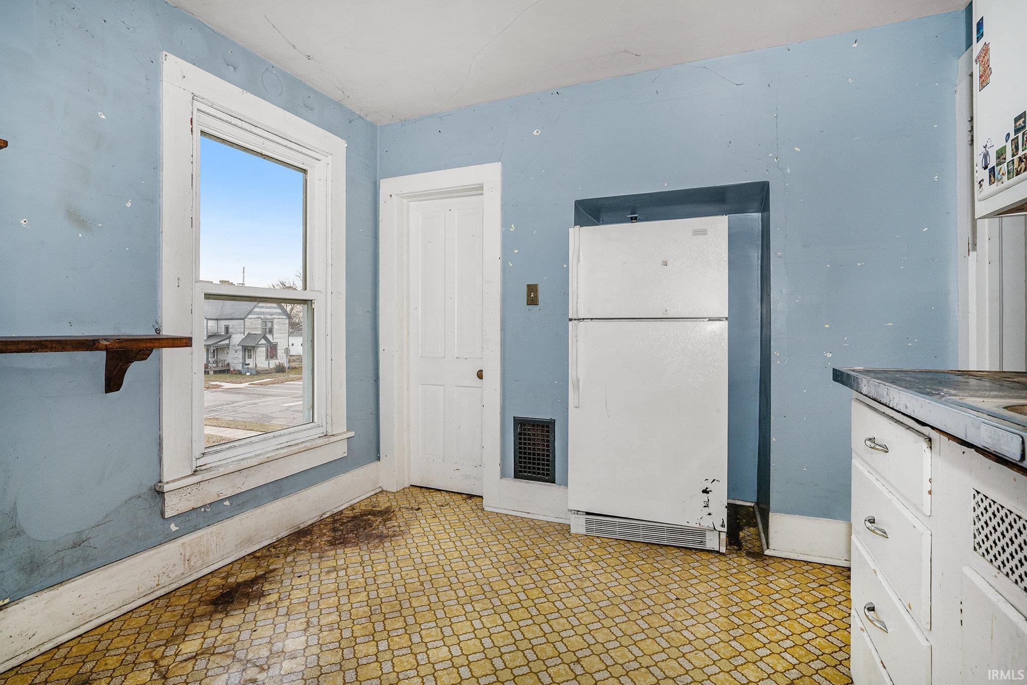 Kitchen with freestanding refrigerator, light flooring, and white cabinets
