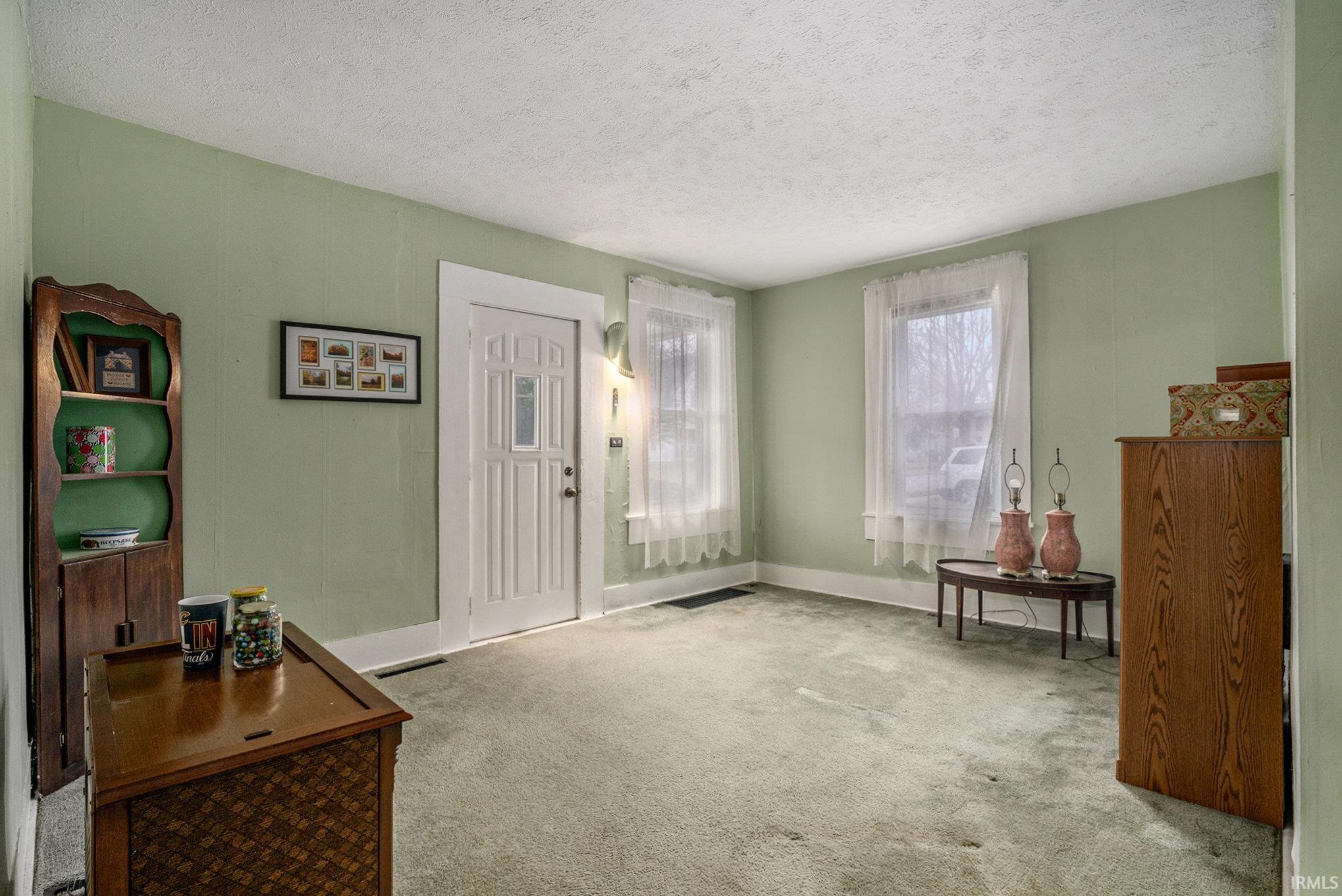 Carpeted foyer entrance with a textured ceiling and baseboards
