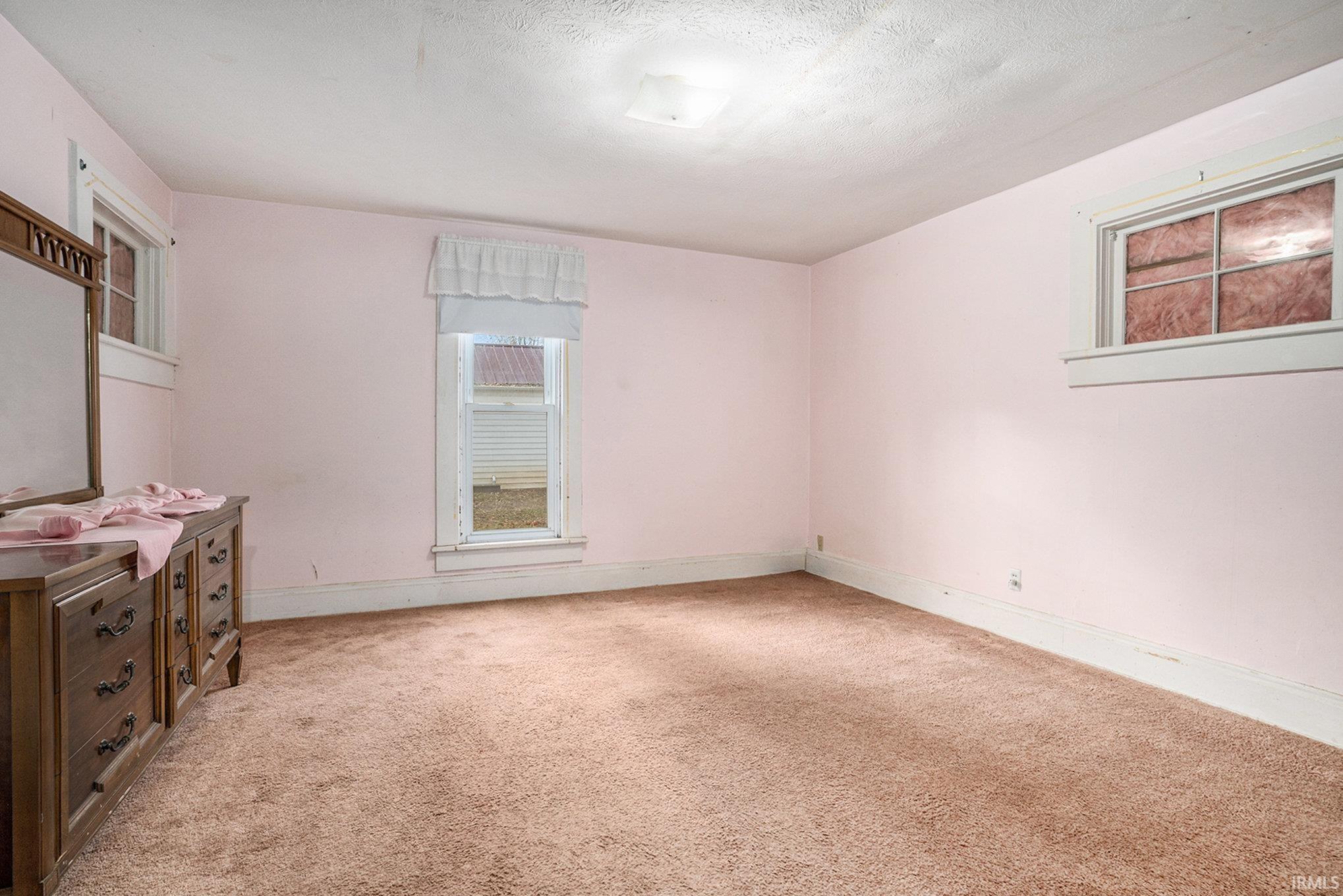 Unfurnished bedroom featuring light colored carpet and a textured ceiling