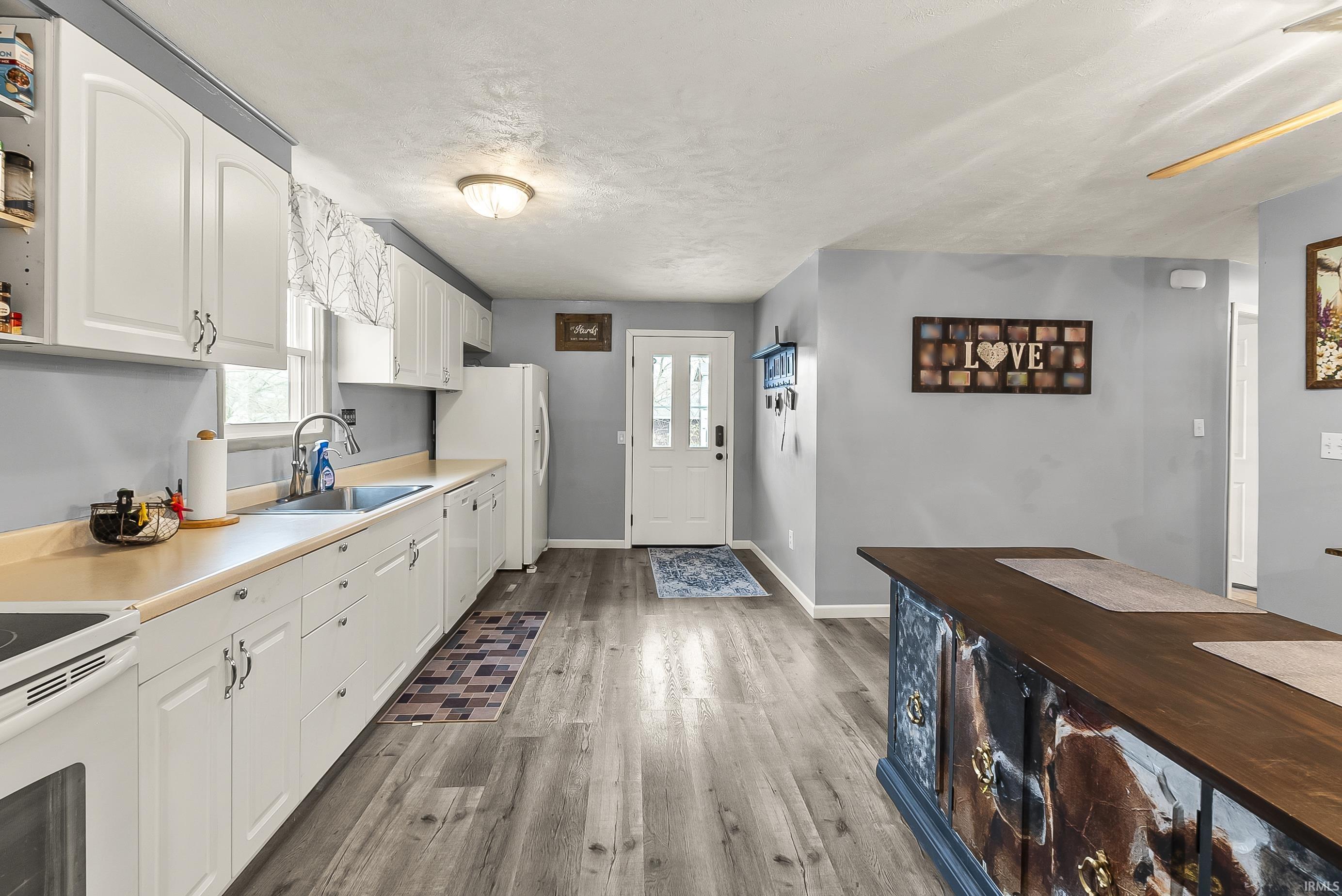 Kitchen featuring white cabinetry, dark wood-style floors, white appliances, a textured ceiling, and butcher block countertops