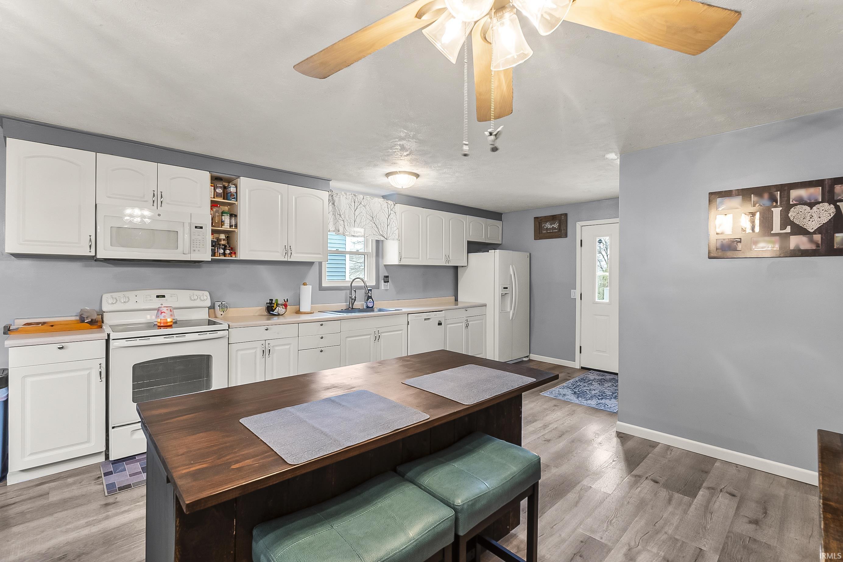 Kitchen with white appliances, white cabinetry, open shelves, light wood-style flooring, and wood counters