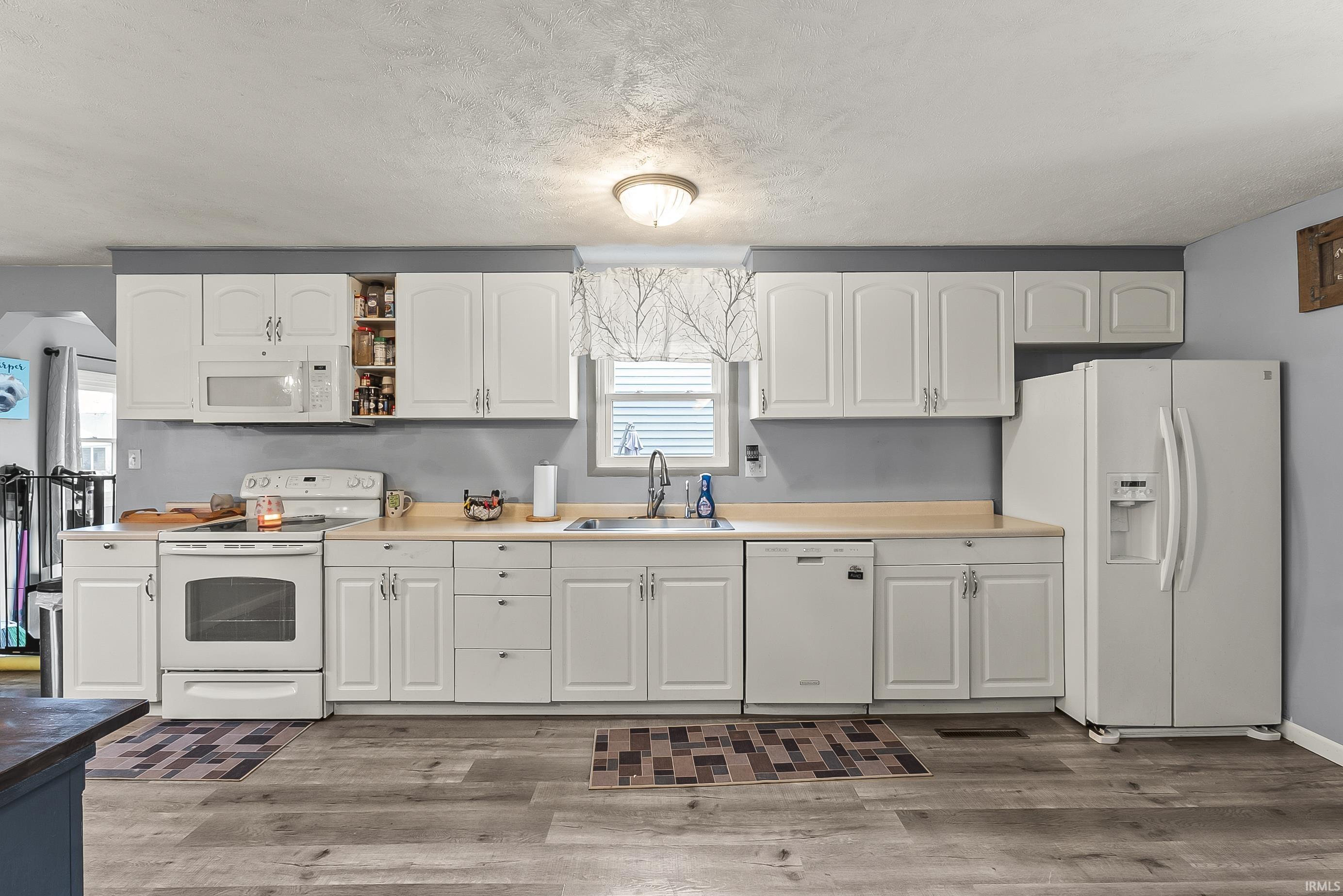 Kitchen featuring white appliances, white cabinetry, open shelves, and a textured ceiling