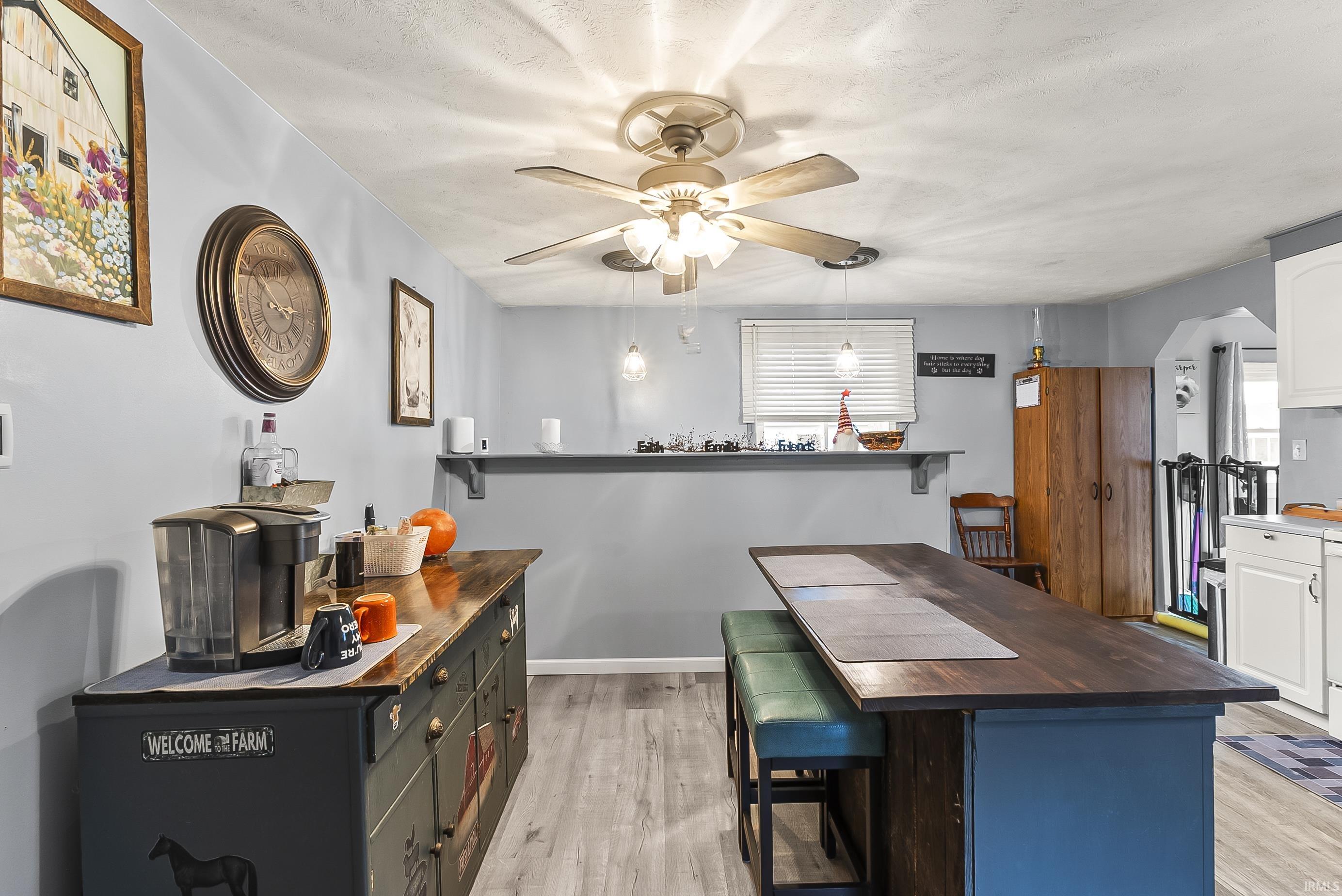 Kitchen with wooden counters, a breakfast bar, ceiling fan, and a textured ceiling