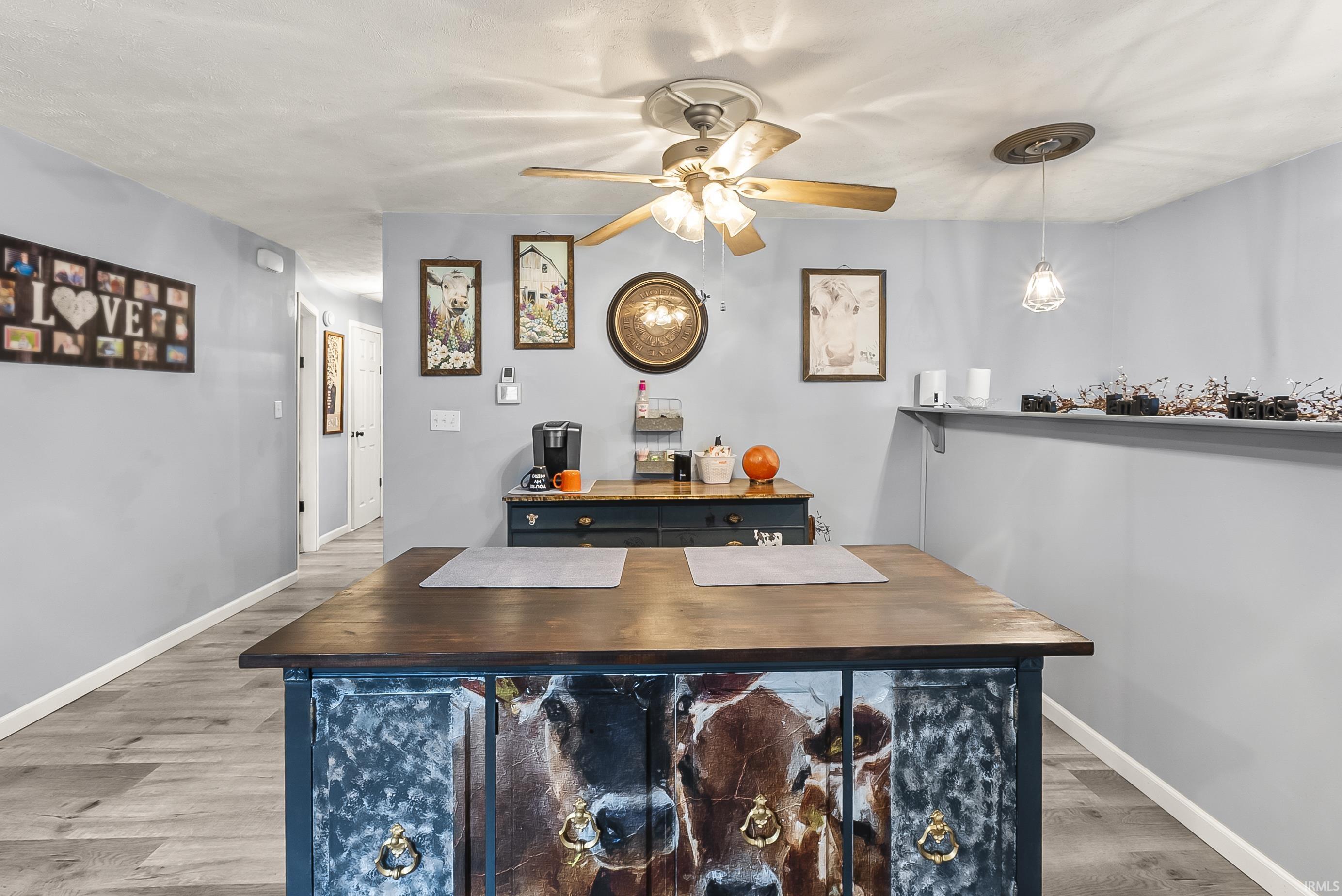 Bar area with butcher block countertops, light wood finished floors, ceiling fan, and hanging light fixtures