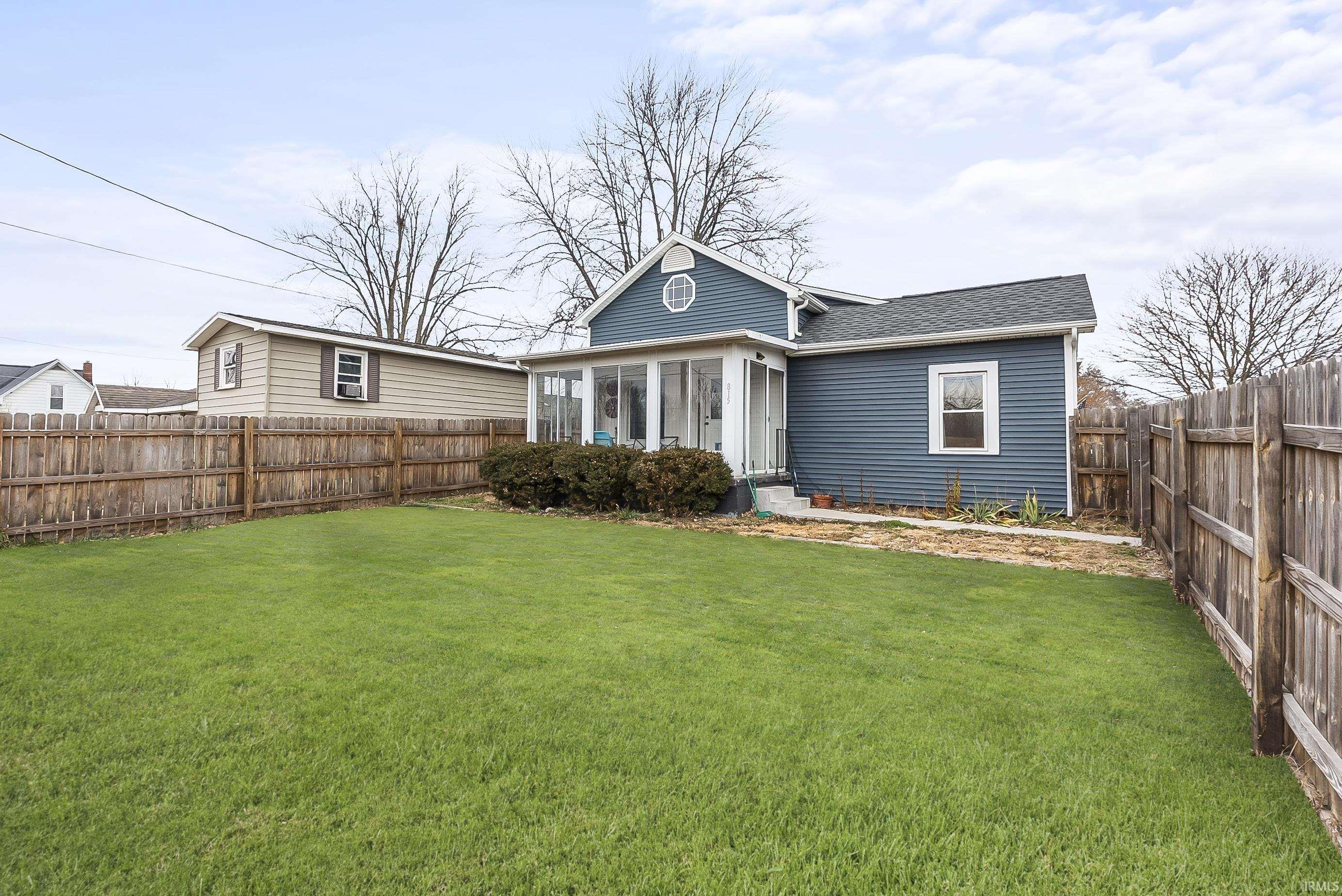 Rear view of house featuring a sunroom, a fenced backyard, and a shingled roof