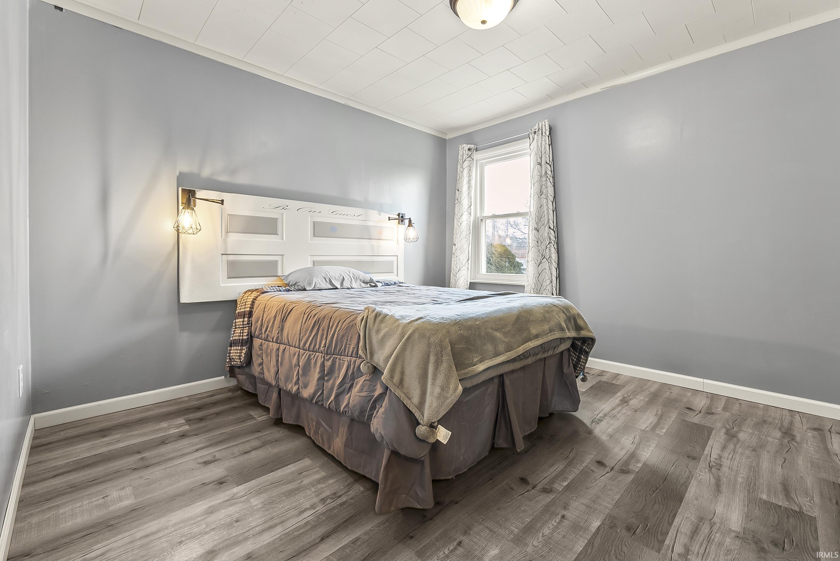 Bedroom featuring crown molding and wood finished floors