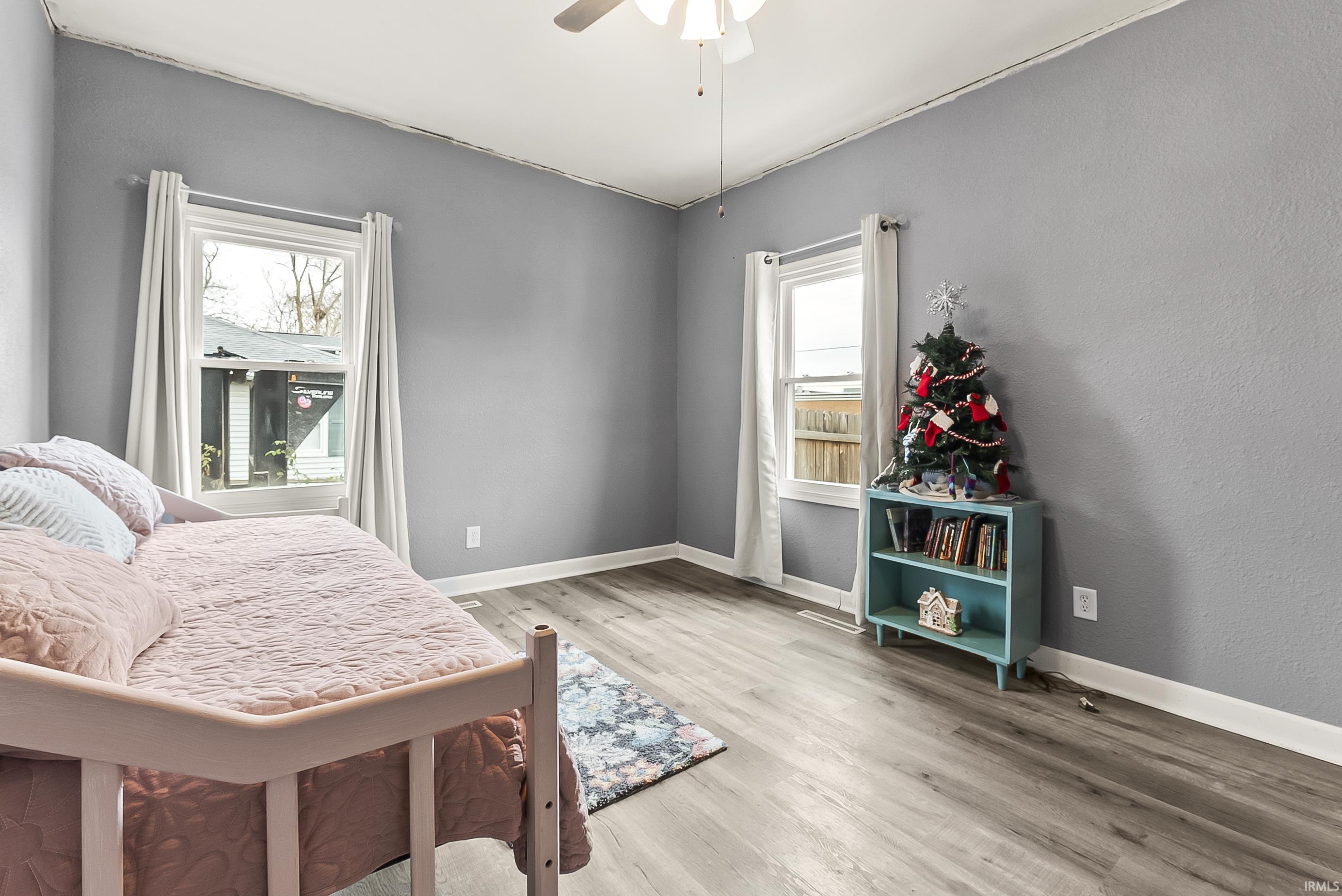 Bedroom with light wood-style flooring, a ceiling fan, and a textured wall