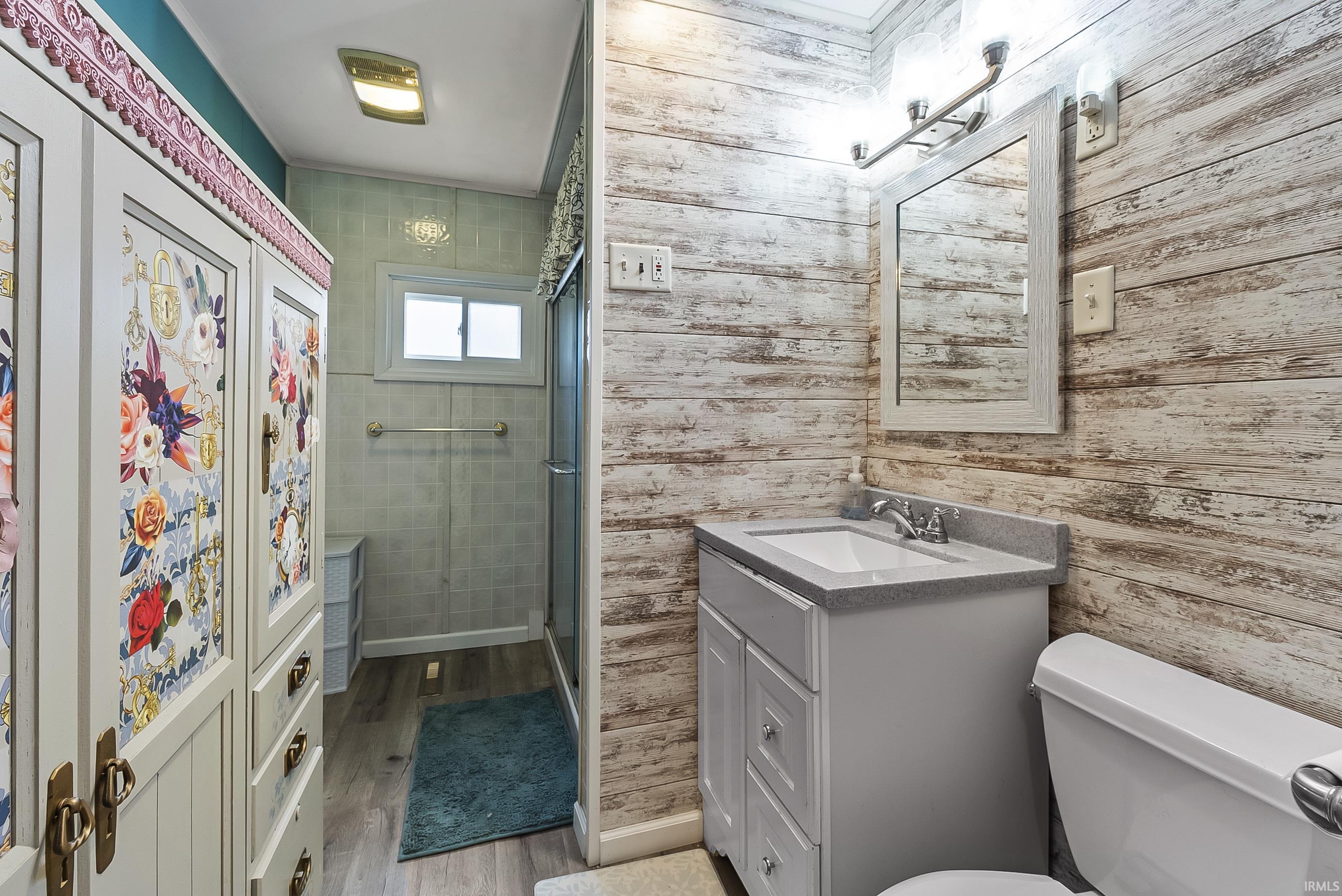 Bathroom featuring vanity, light wood finished floors, and a stall shower