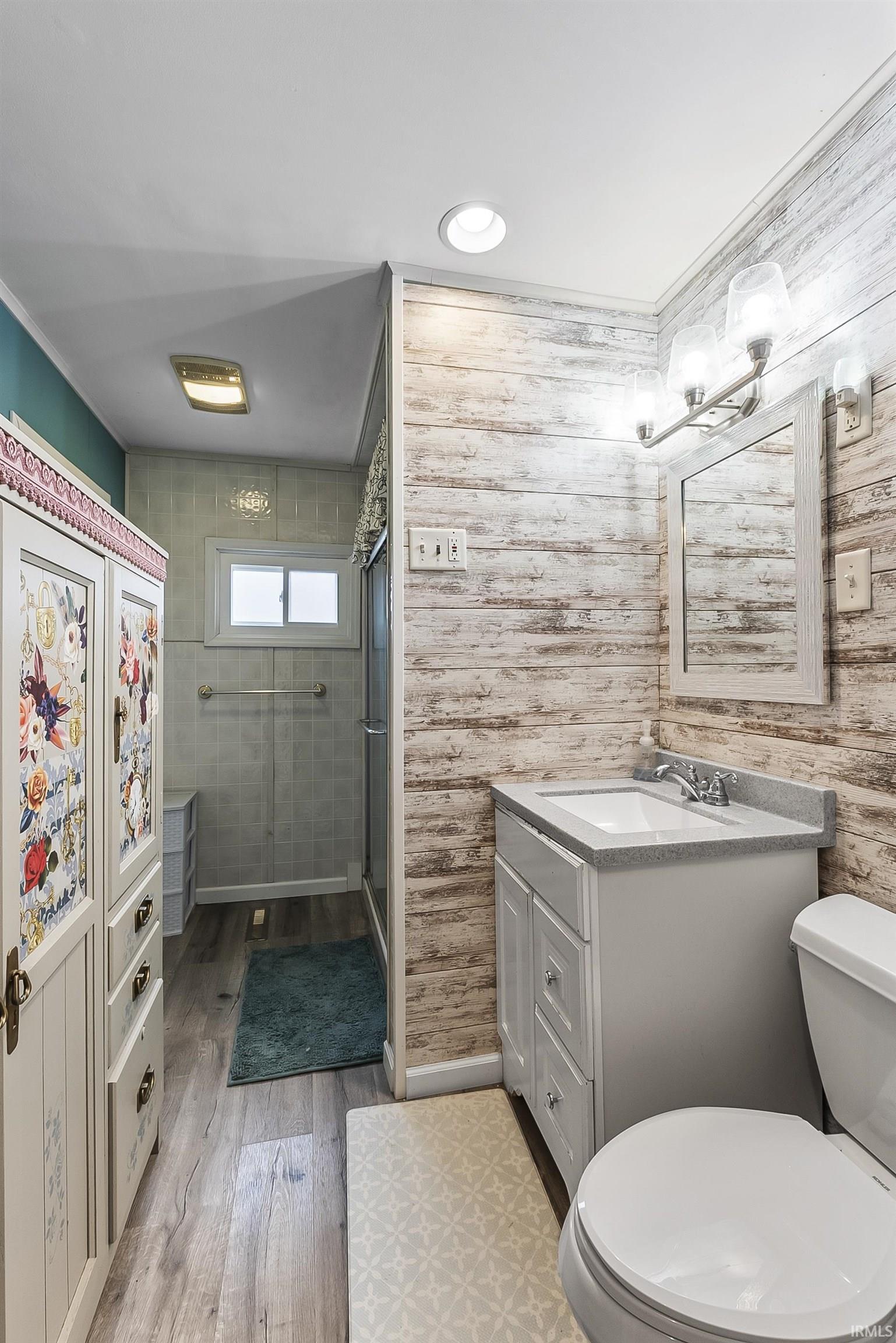 Full bathroom featuring vanity, a shower stall, and light wood finished floors
