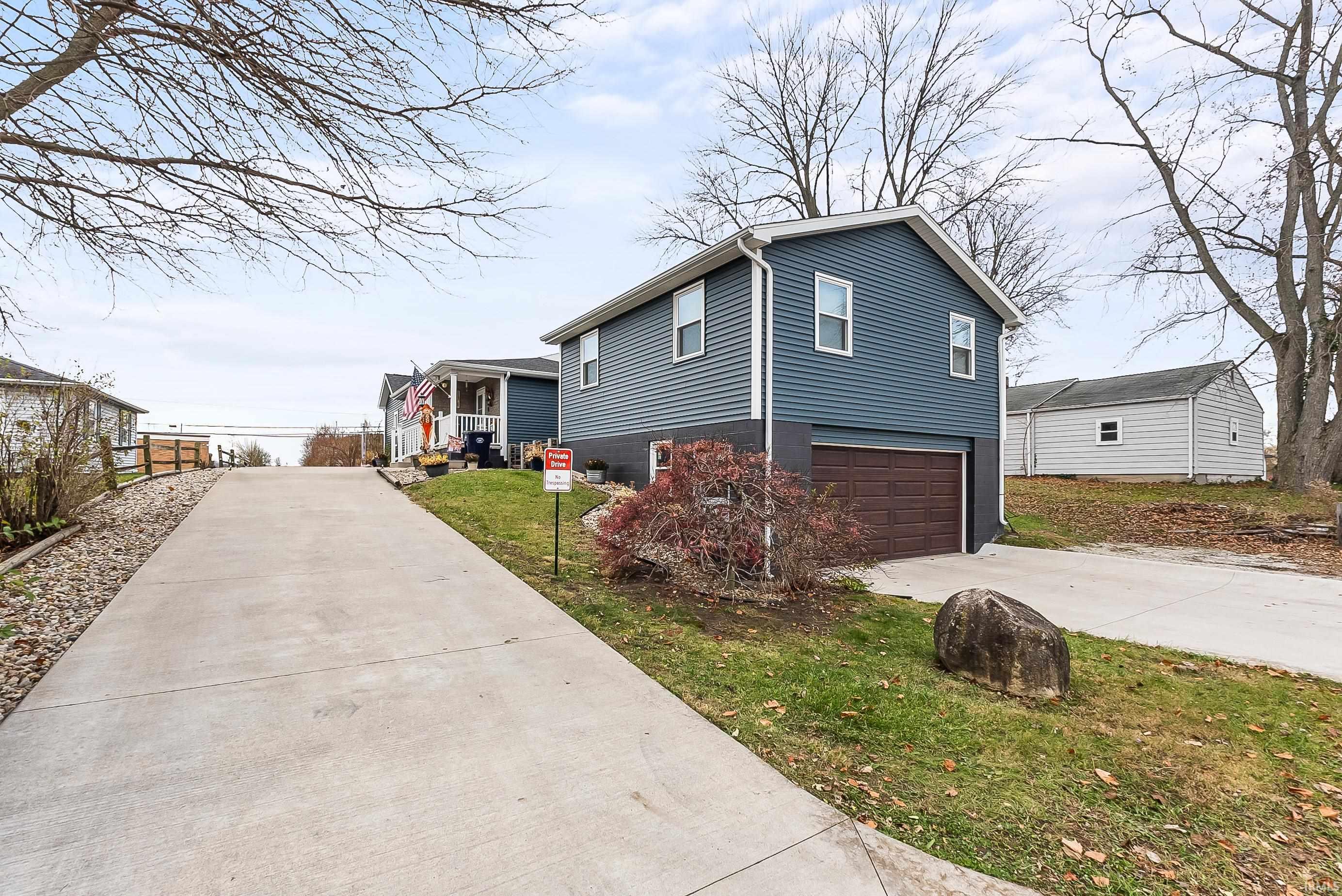 View of property exterior featuring driveway, a yard, and a garage
