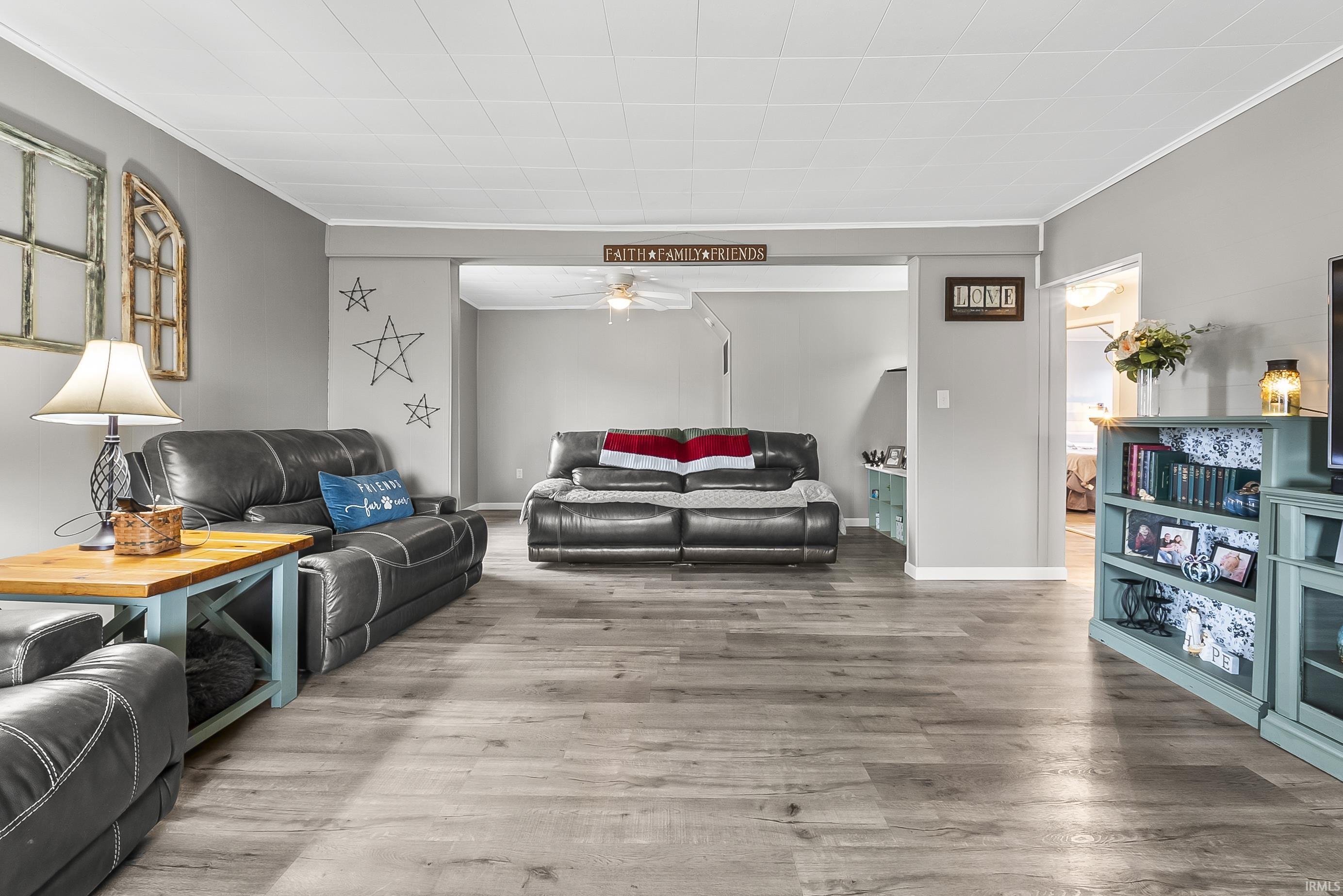Living room featuring ornamental molding, wood finished floors, and a ceiling fan
