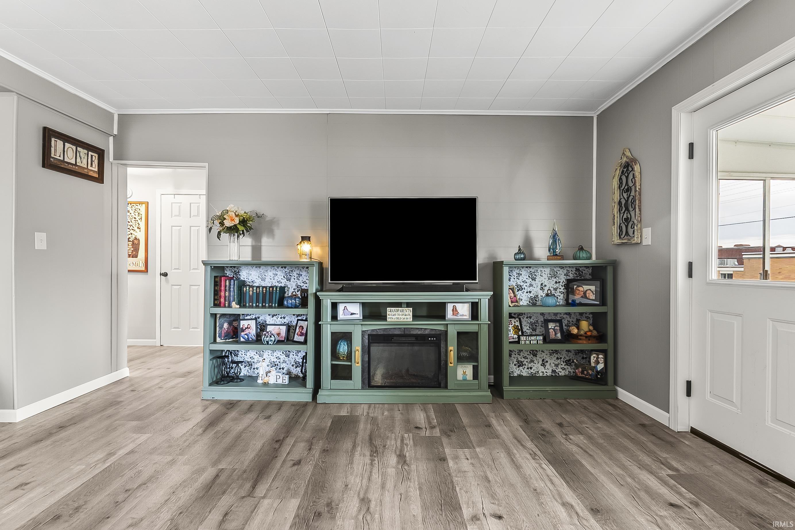 Living room featuring ornamental molding, wood finished floors, and a glass covered fireplace