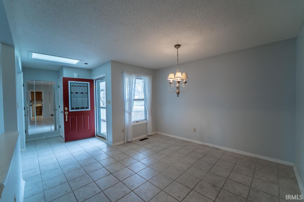 Entrance foyer featuring a textured ceiling, a chandelier, and light tile patterned flooring
