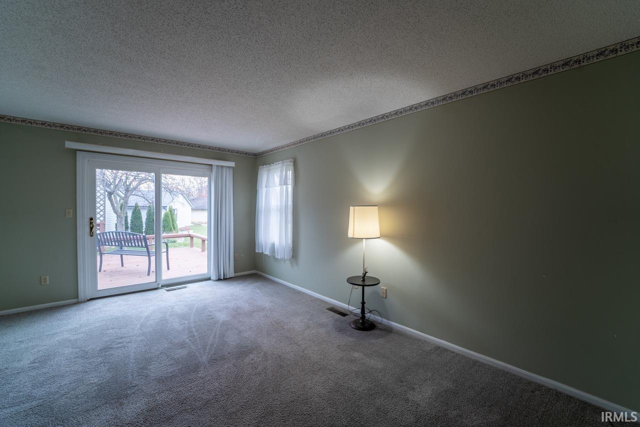 Carpeted spare room with a textured ceiling and baseboards