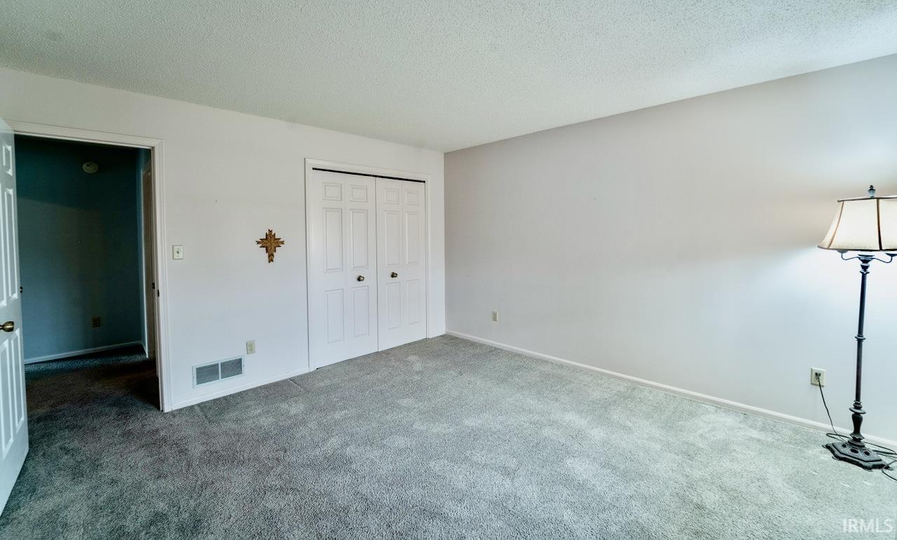 Unfurnished bedroom with a textured ceiling, carpet, and a closet