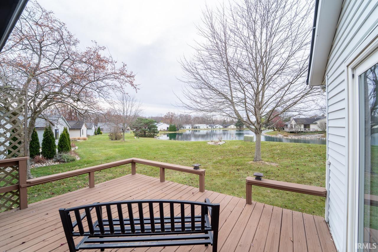 Wooden terrace with a water view, a yard, and a residential view