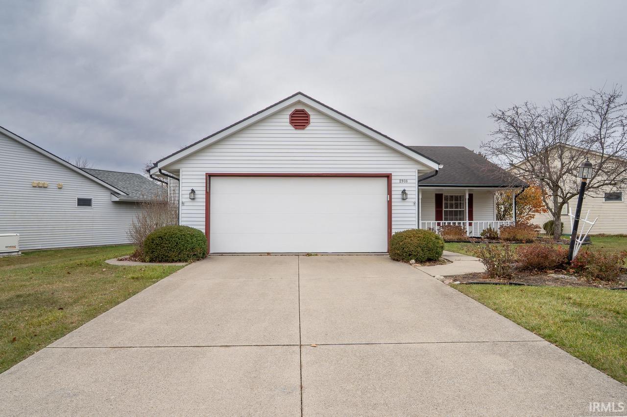 Single story home featuring a porch, driveway, a front yard, and an attached garage