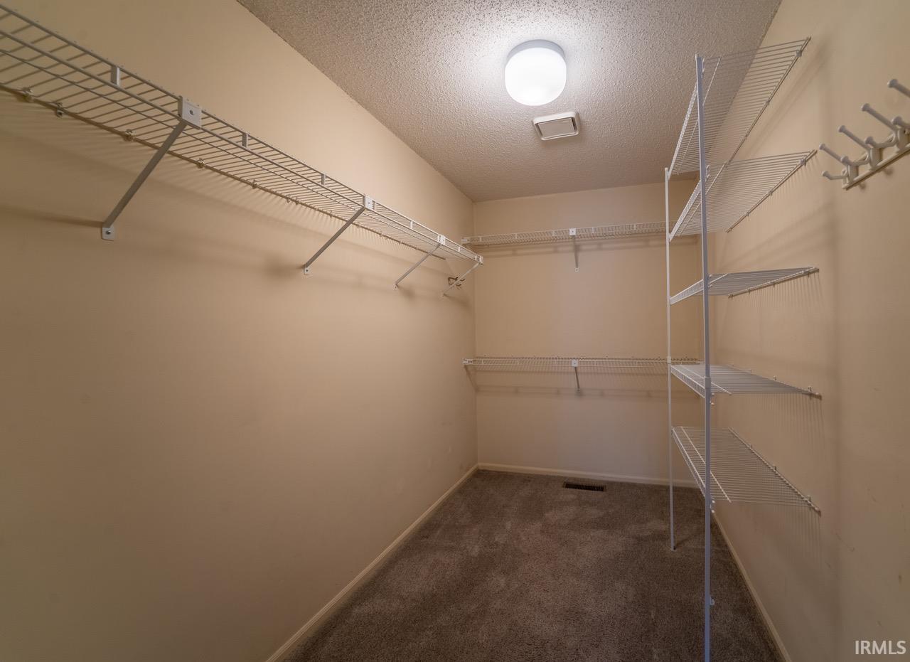 Walk in closet featuring dark carpet