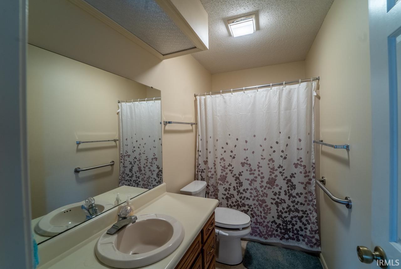 Full bath with a textured ceiling, a shower with curtain, and vanity