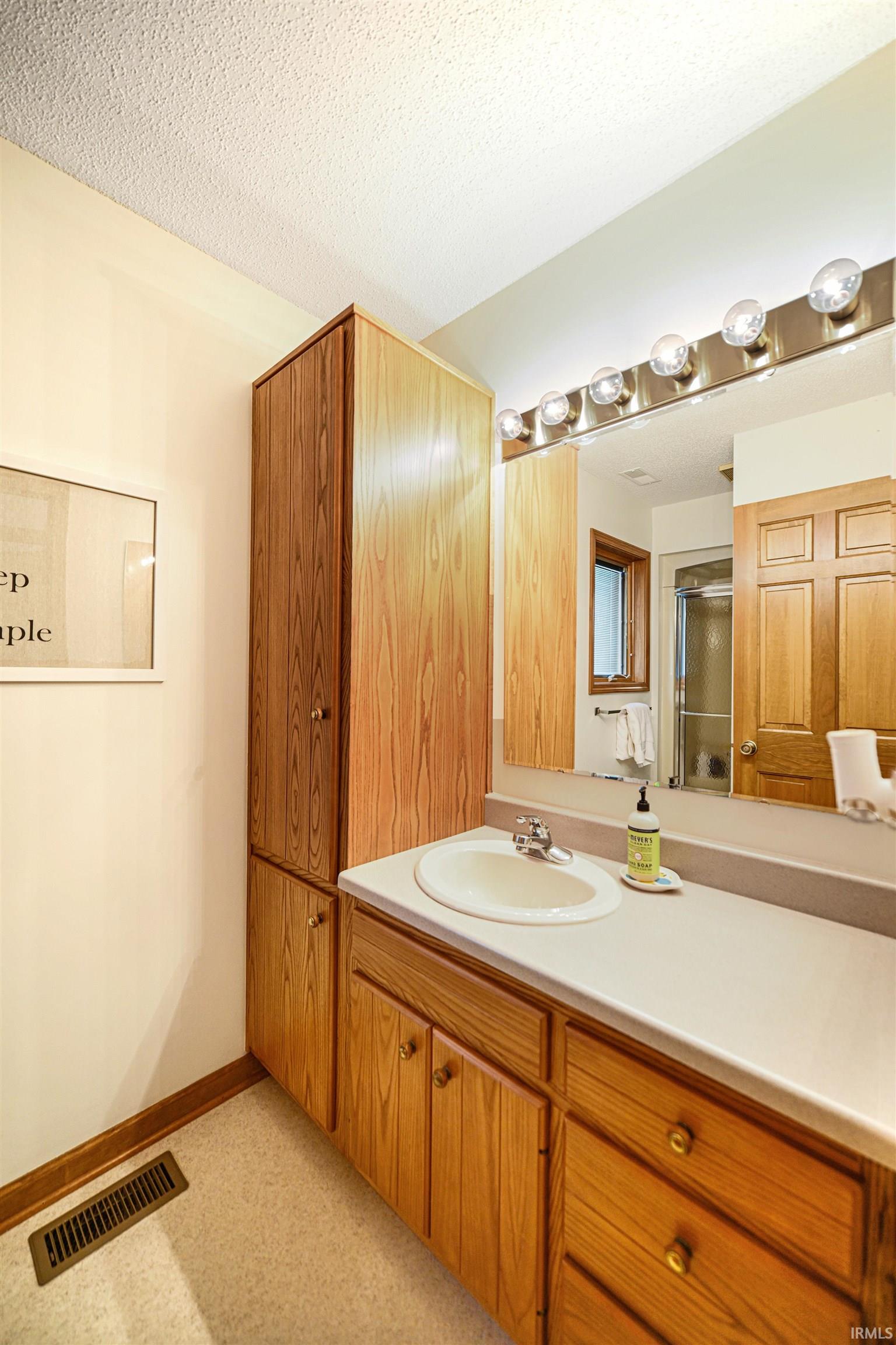 Full bathroom with vanity, a textured ceiling, and a shower stall
