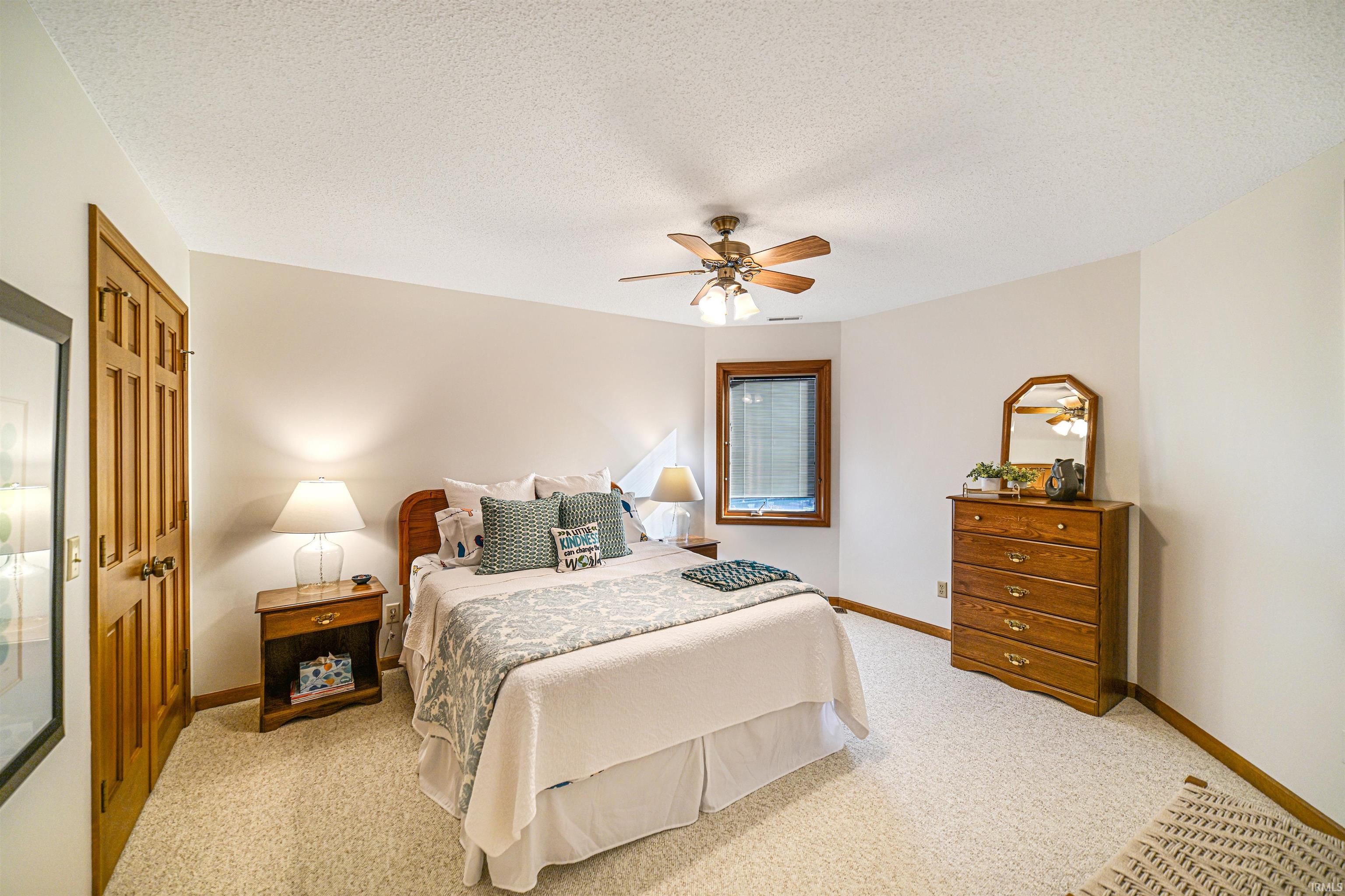 Bedroom with a textured ceiling, a ceiling fan, light colored carpet, and a closet
