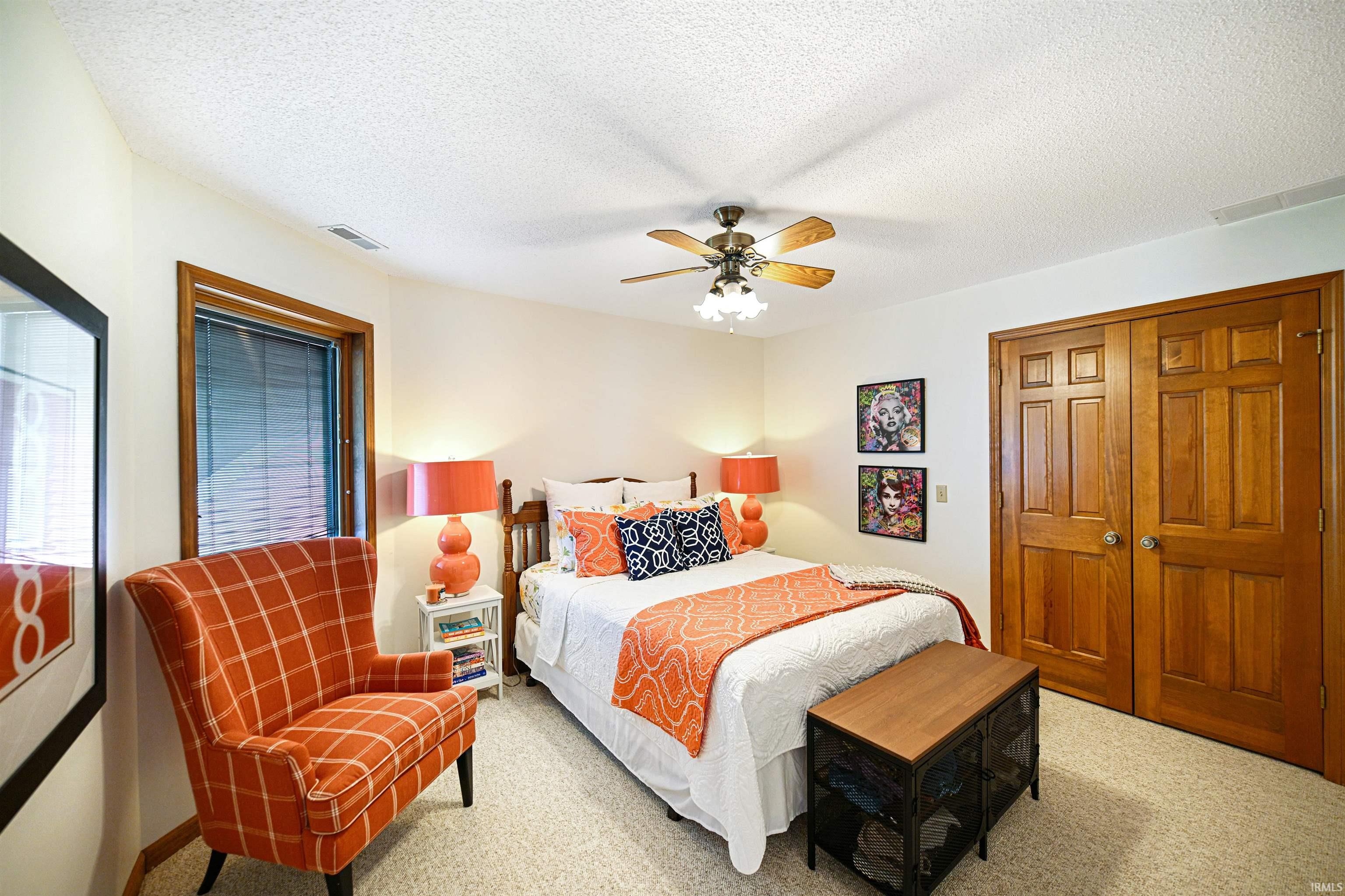 Bedroom featuring a textured ceiling, a closet, ceiling fan, and carpet