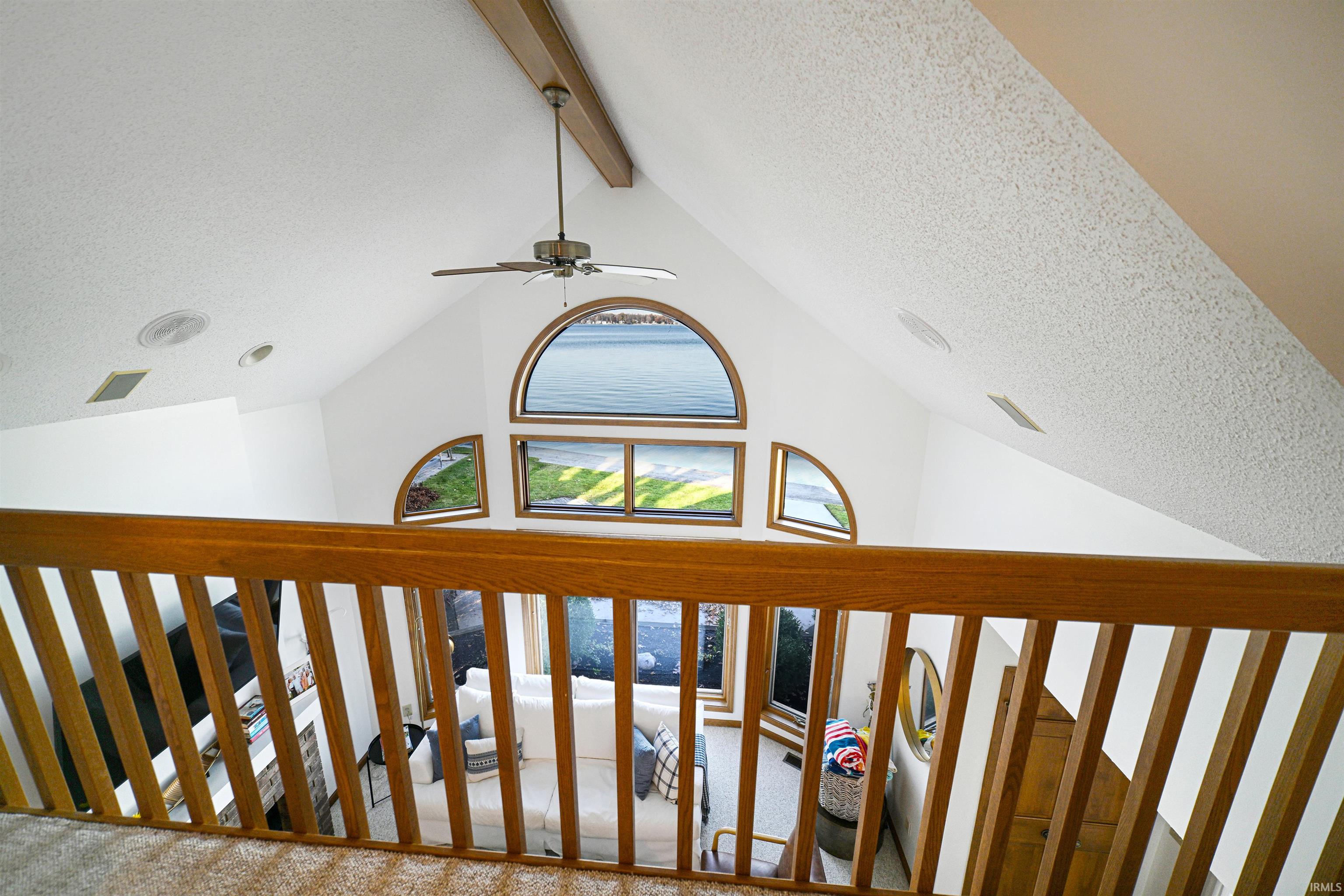 Detailed view of a textured ceiling, beamed ceiling, and a ceiling fan