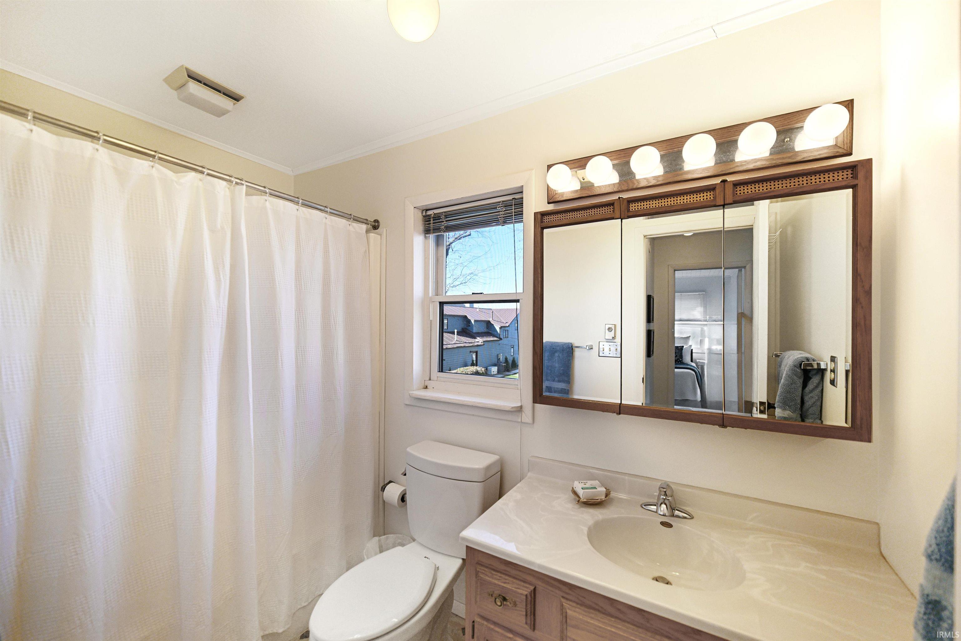 Bathroom featuring curtained shower, vanity, and crown molding