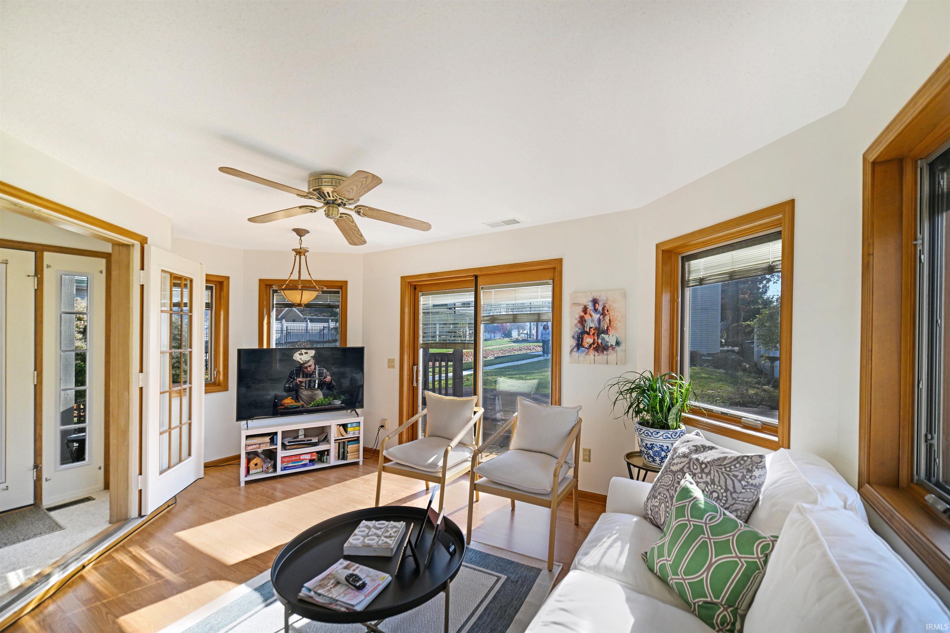 Living area with healthy amount of natural light, wood finished floors, and a ceiling fan