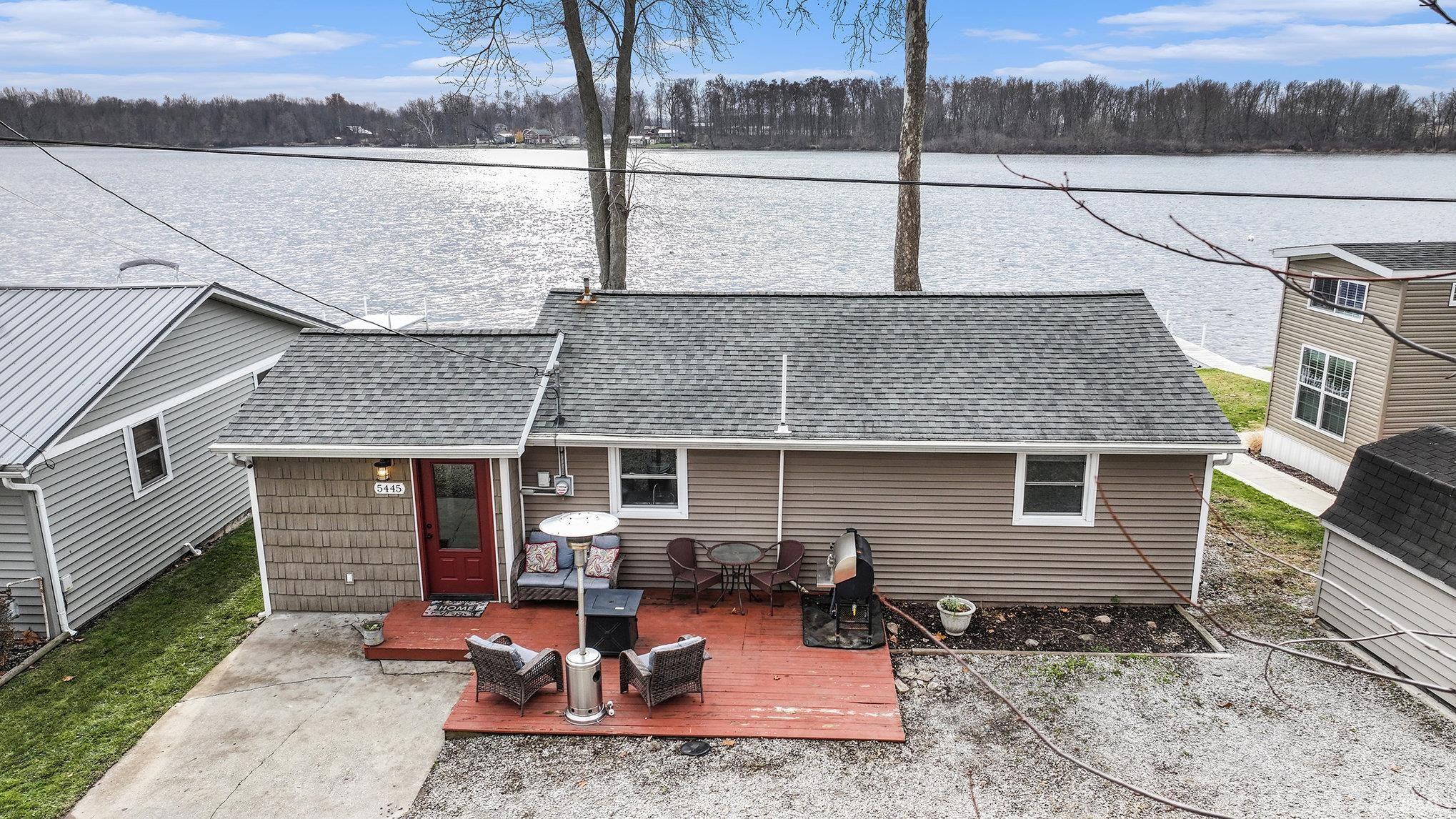 Rear view of property featuring roof with shingles, a deck with water view, and outdoor dining area