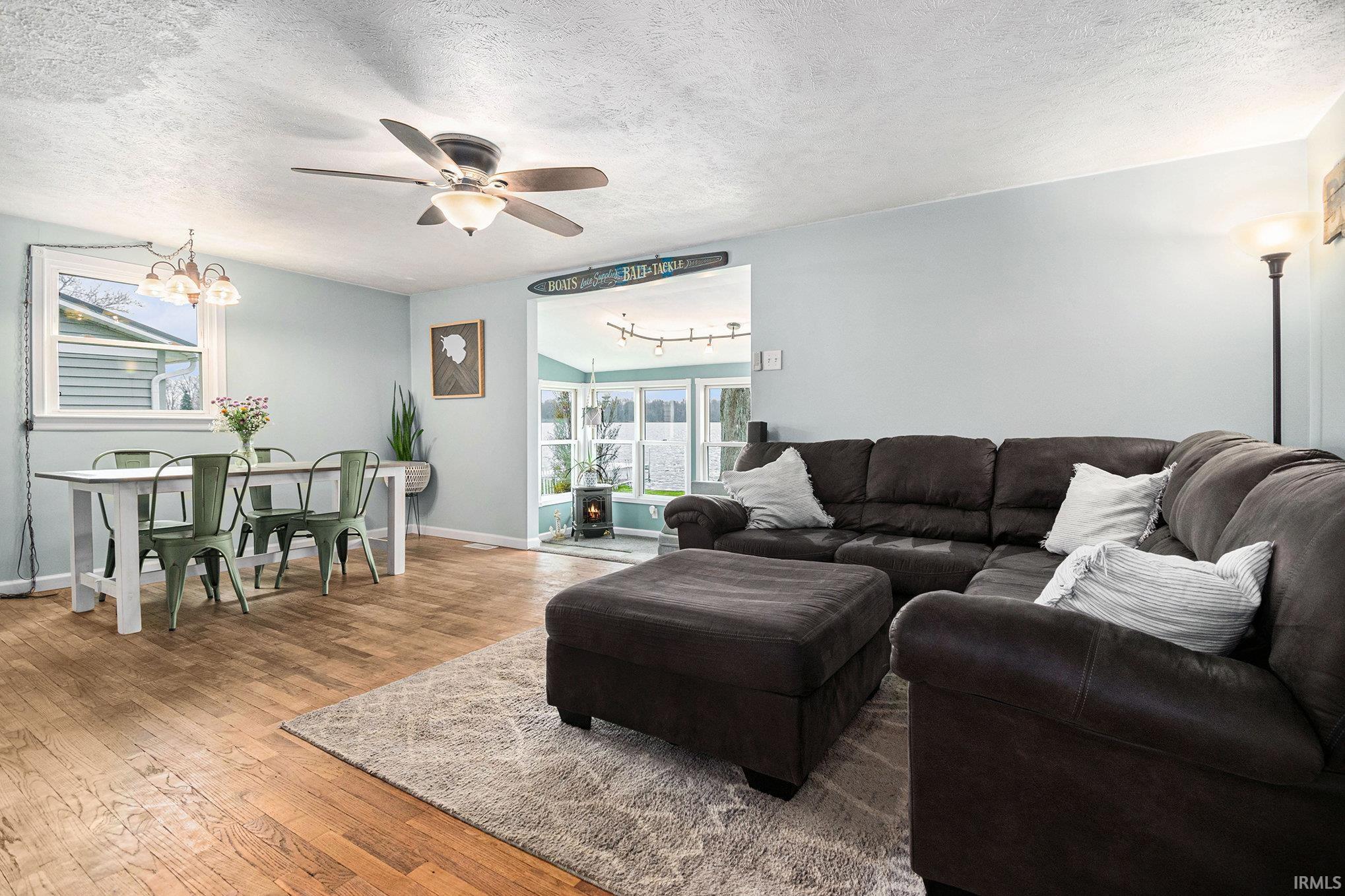 Living room featuring a textured ceiling, a chandelier, hardwood / wood-style flooring, and ceiling fan