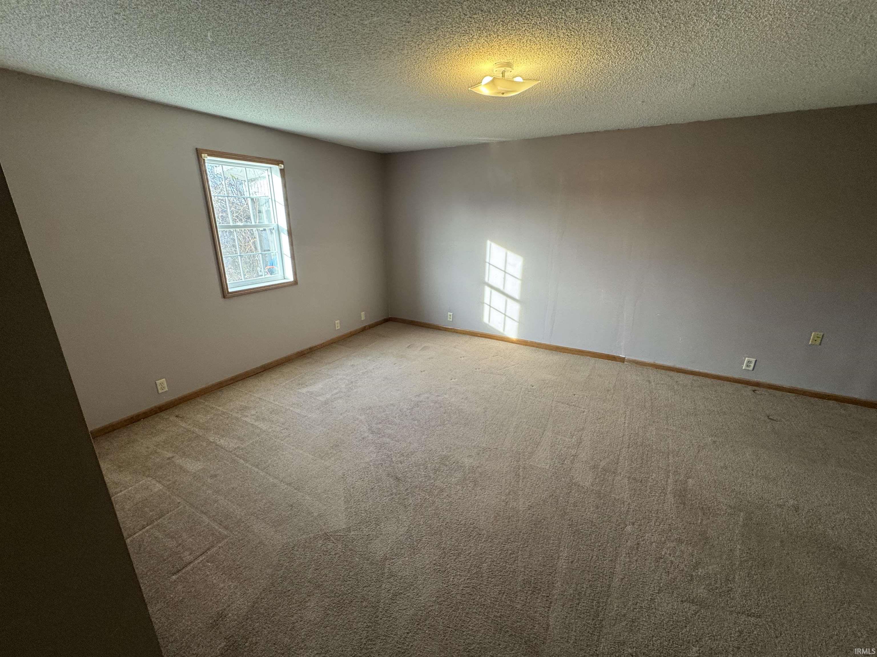 Unfurnished room with a textured ceiling and light carpet