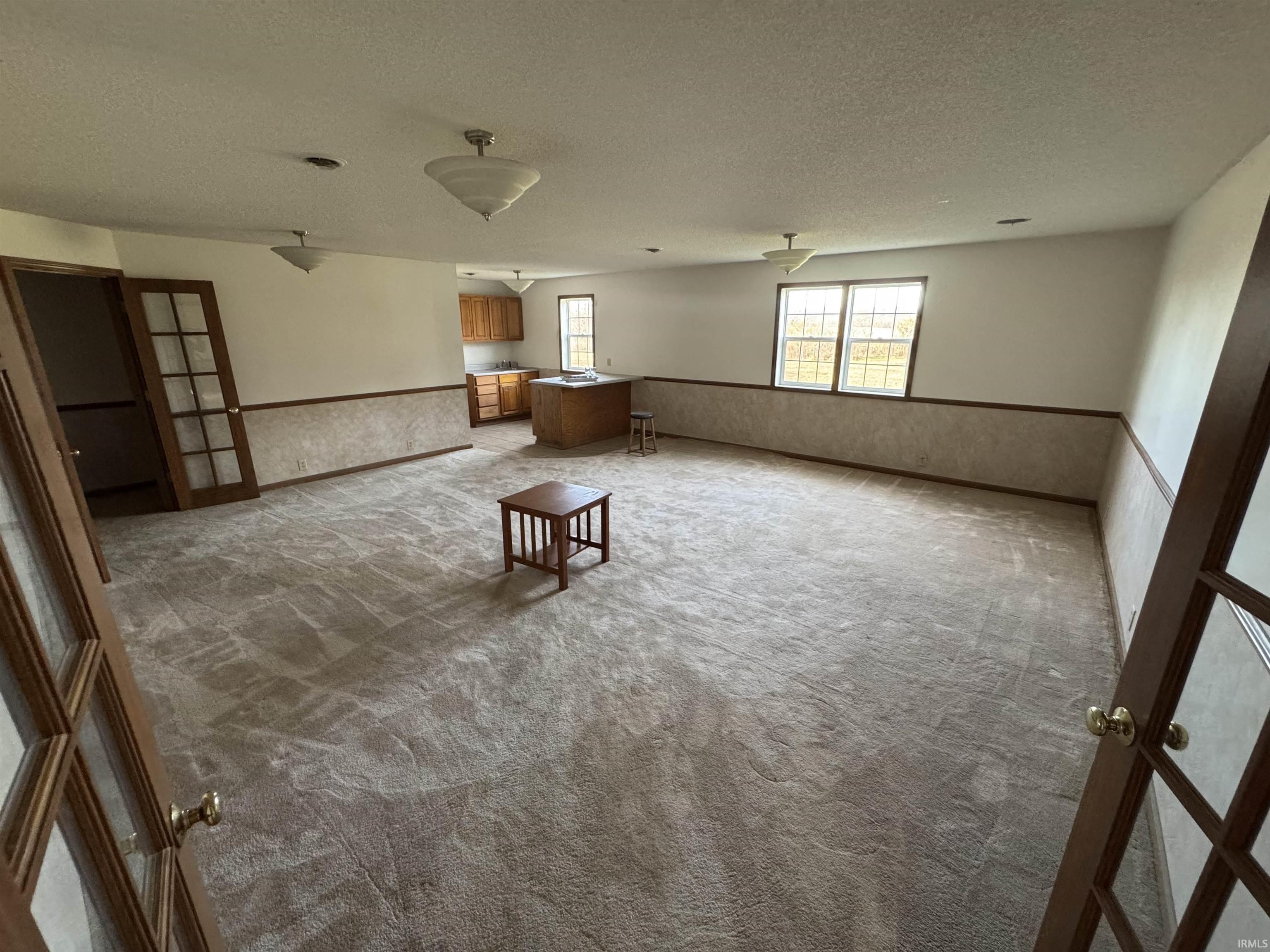 Spare room with a wainscoted wall, a textured ceiling, and carpet floors