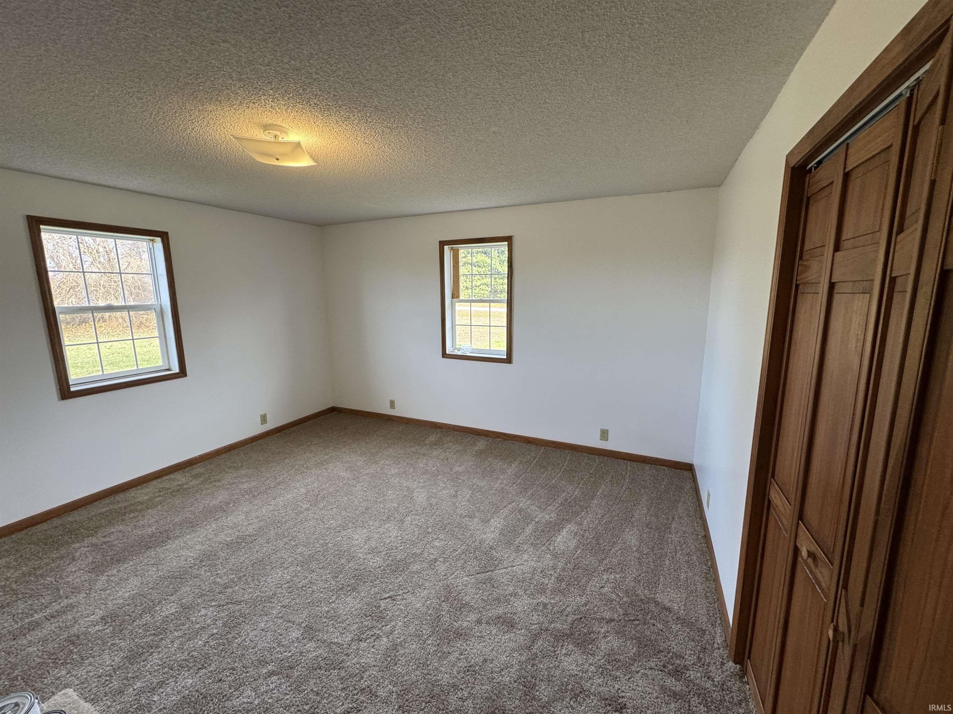 Unfurnished bedroom featuring a closet, light colored carpet, and a textured ceiling
