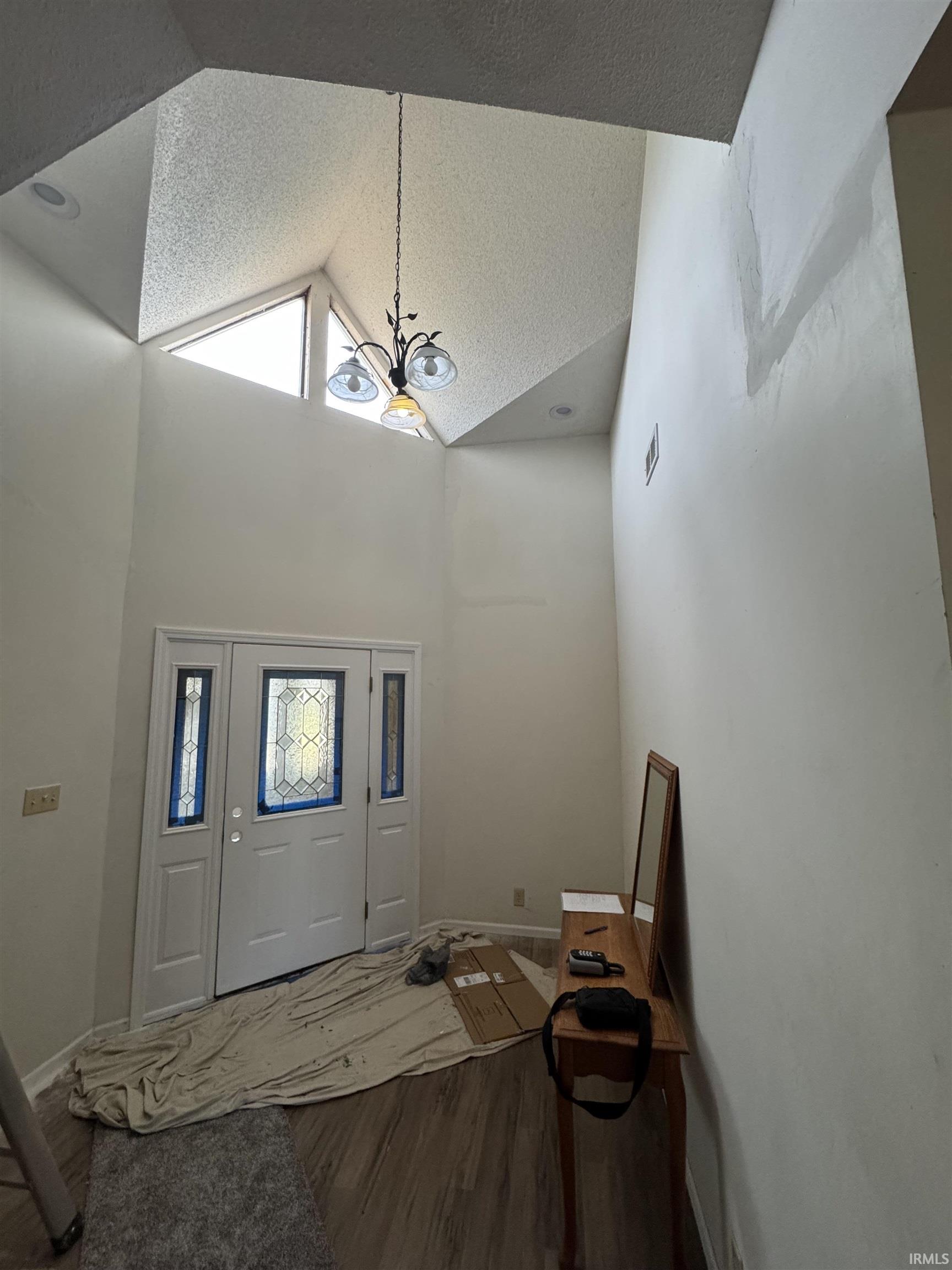 Foyer featuring a textured ceiling, wood finished floors, and high vaulted ceiling