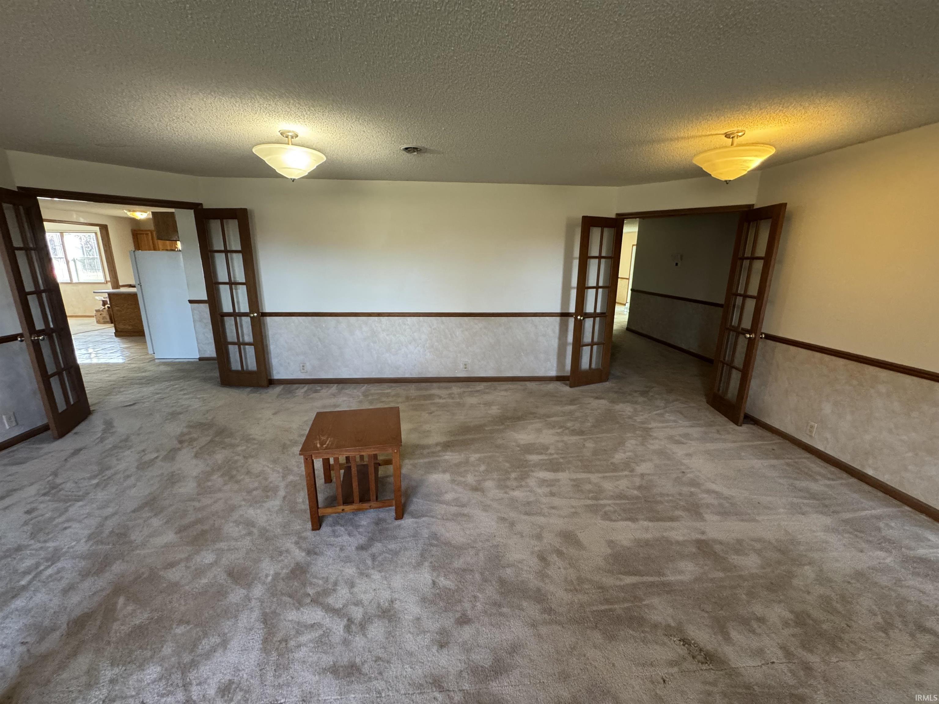 Carpeted spare room with french doors and a textured ceiling