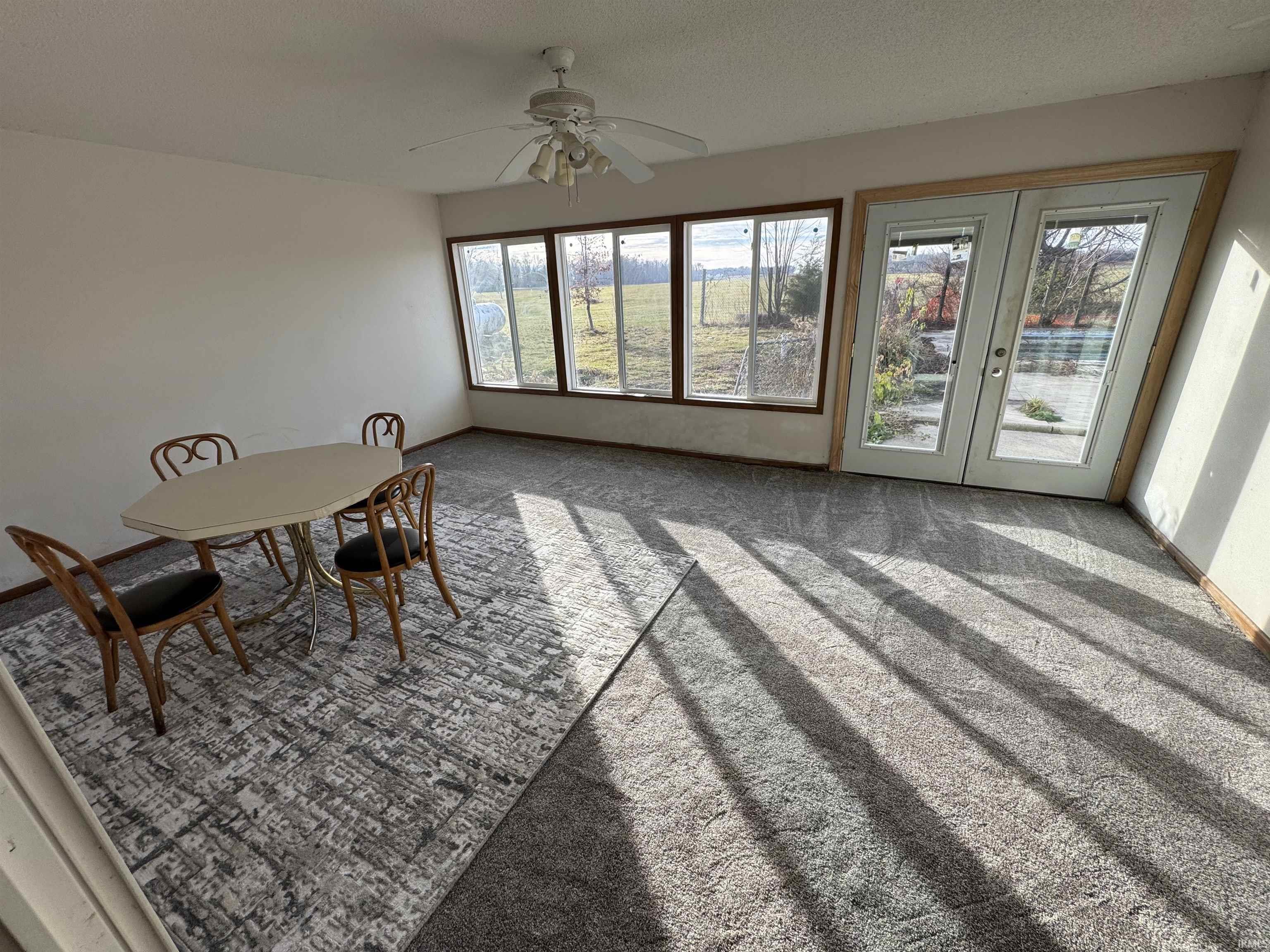 Carpeted dining room featuring french doors, a textured ceiling, and a ceiling fan