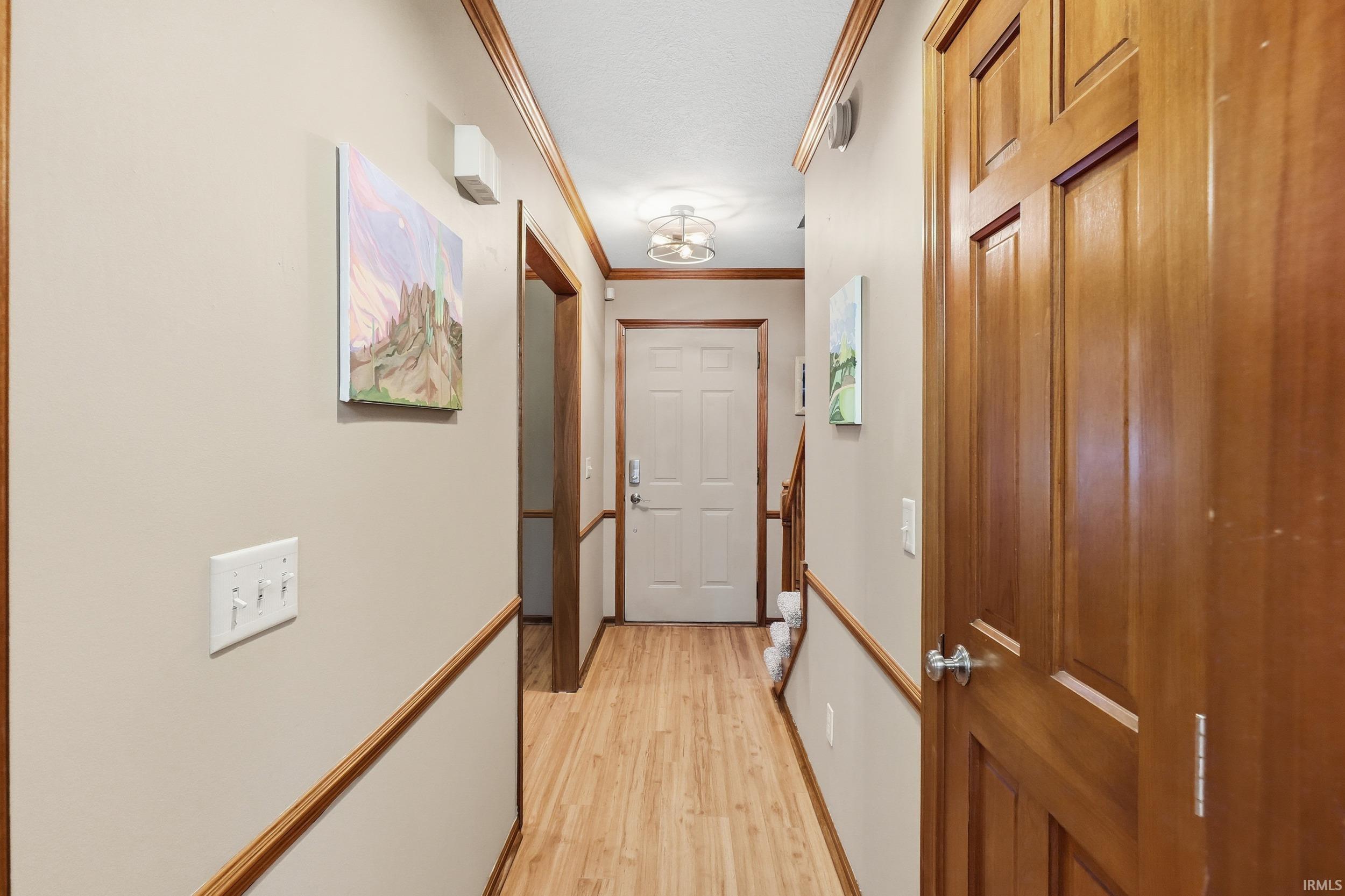 Hallway with light wood finished floors and crown molding